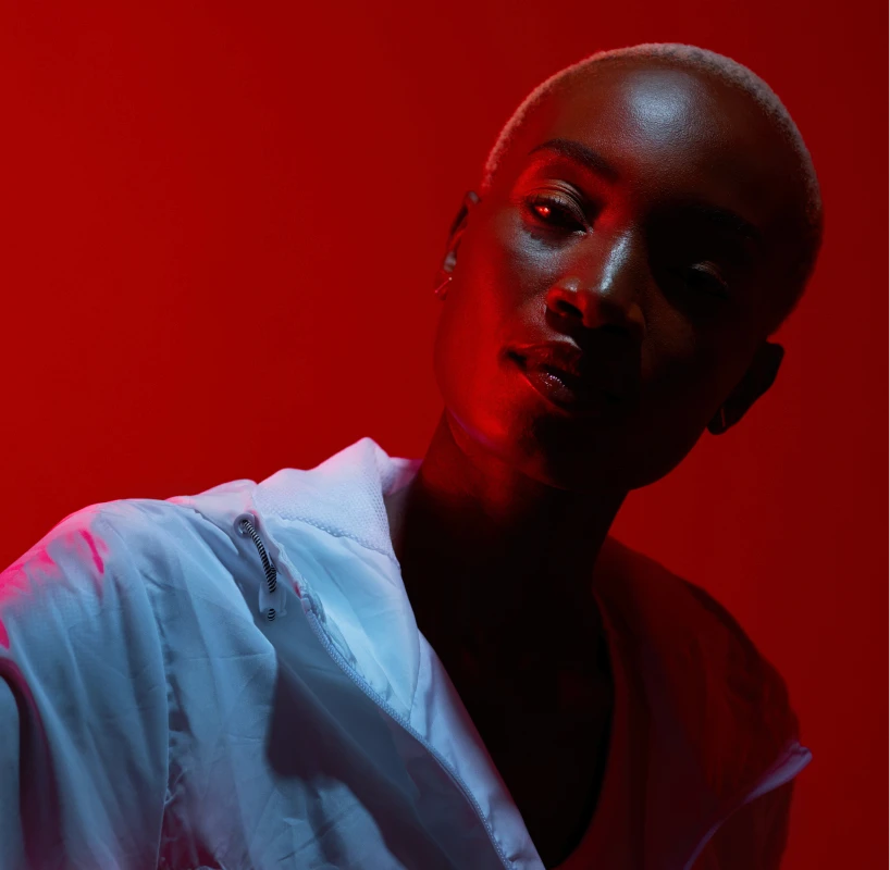 Striking portrait in red and blue neon light of a person with a shaved head.