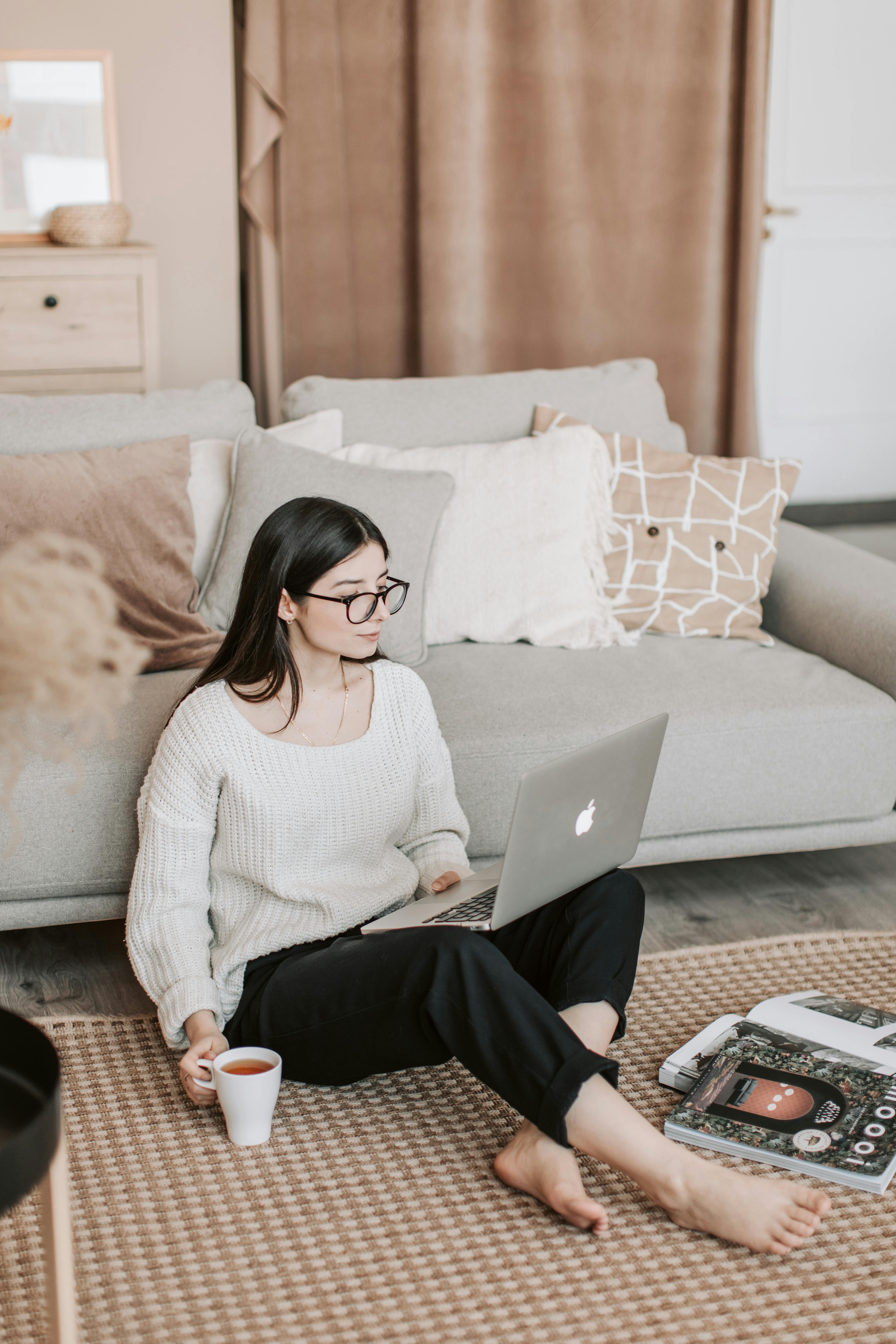 Woman sitting on floor with laptop, setting up her online wellness business from home