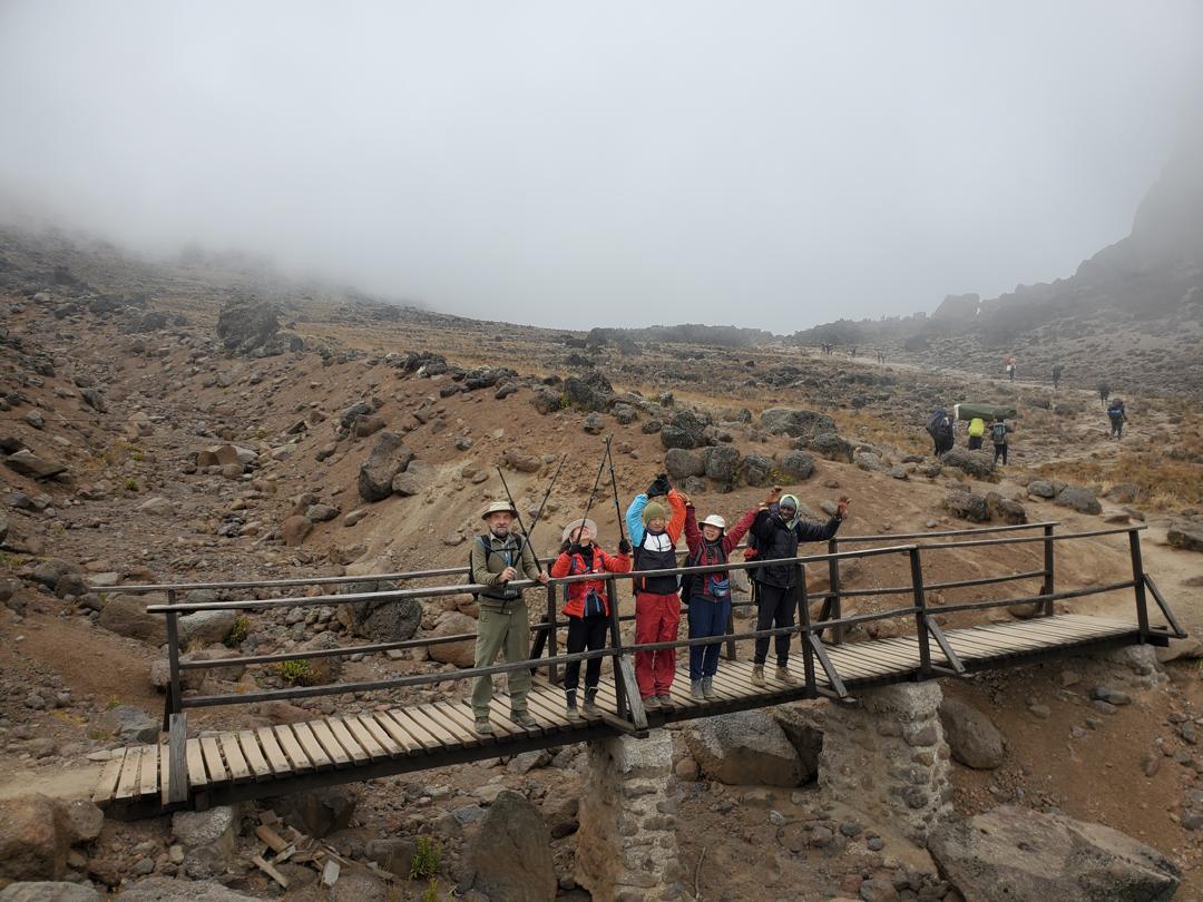 Lone traveler walking across golden dunes in AlUla desert, leaving footprints under clear morning light.