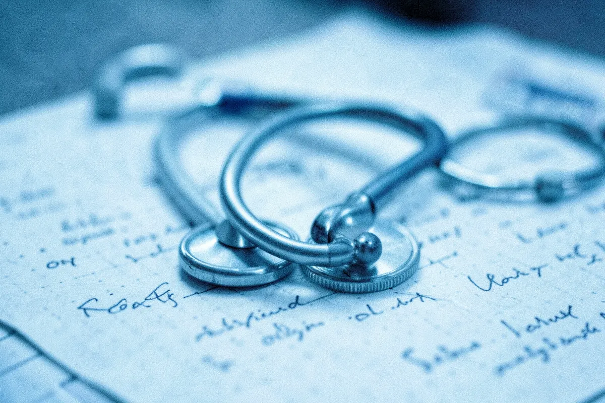 A close-up of a stethoscope forming a heart shape over a patient's chart.