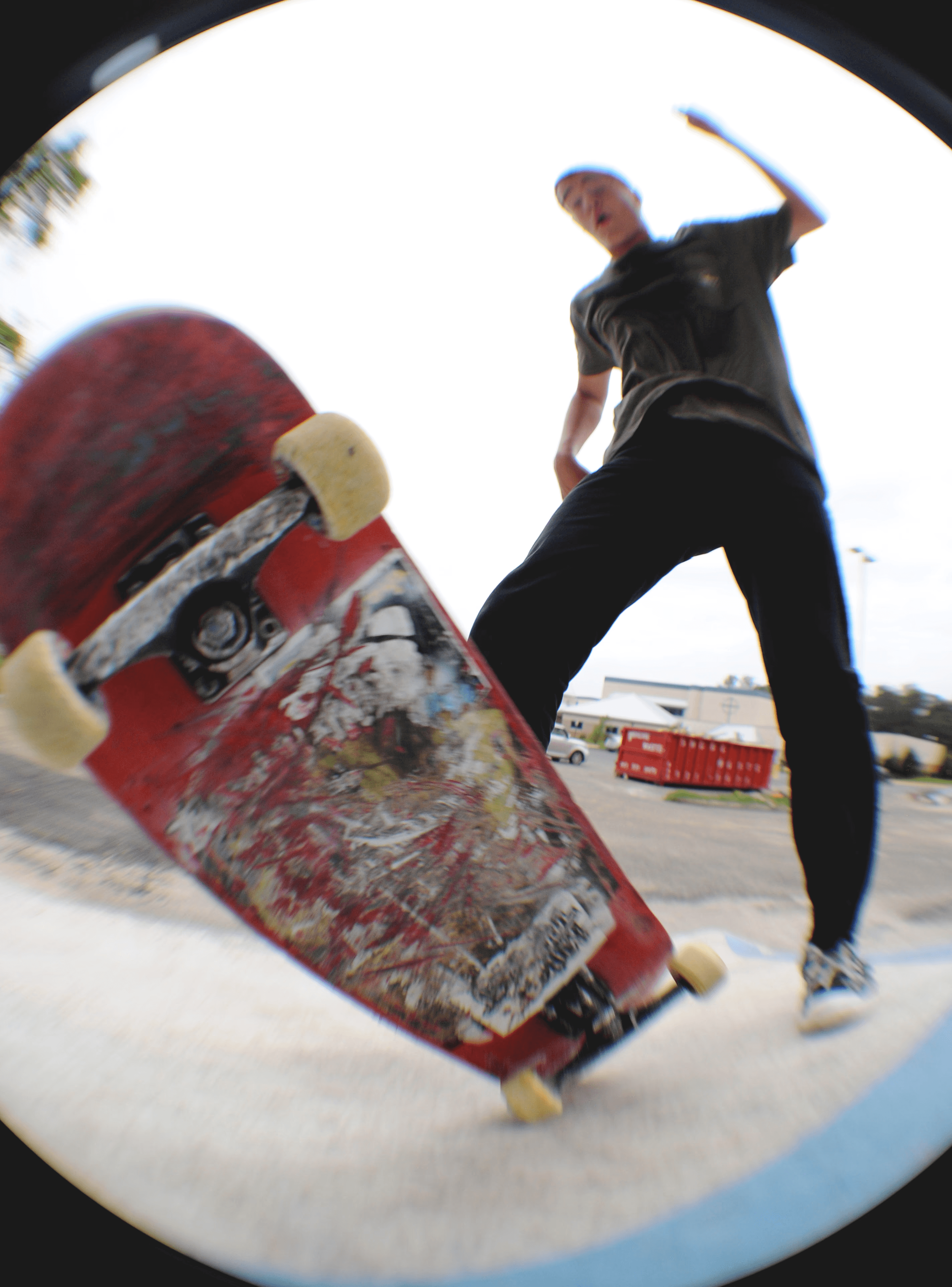Fish eye photography of a skateboarder losing control of the board as it nearly collides with the camera lens.