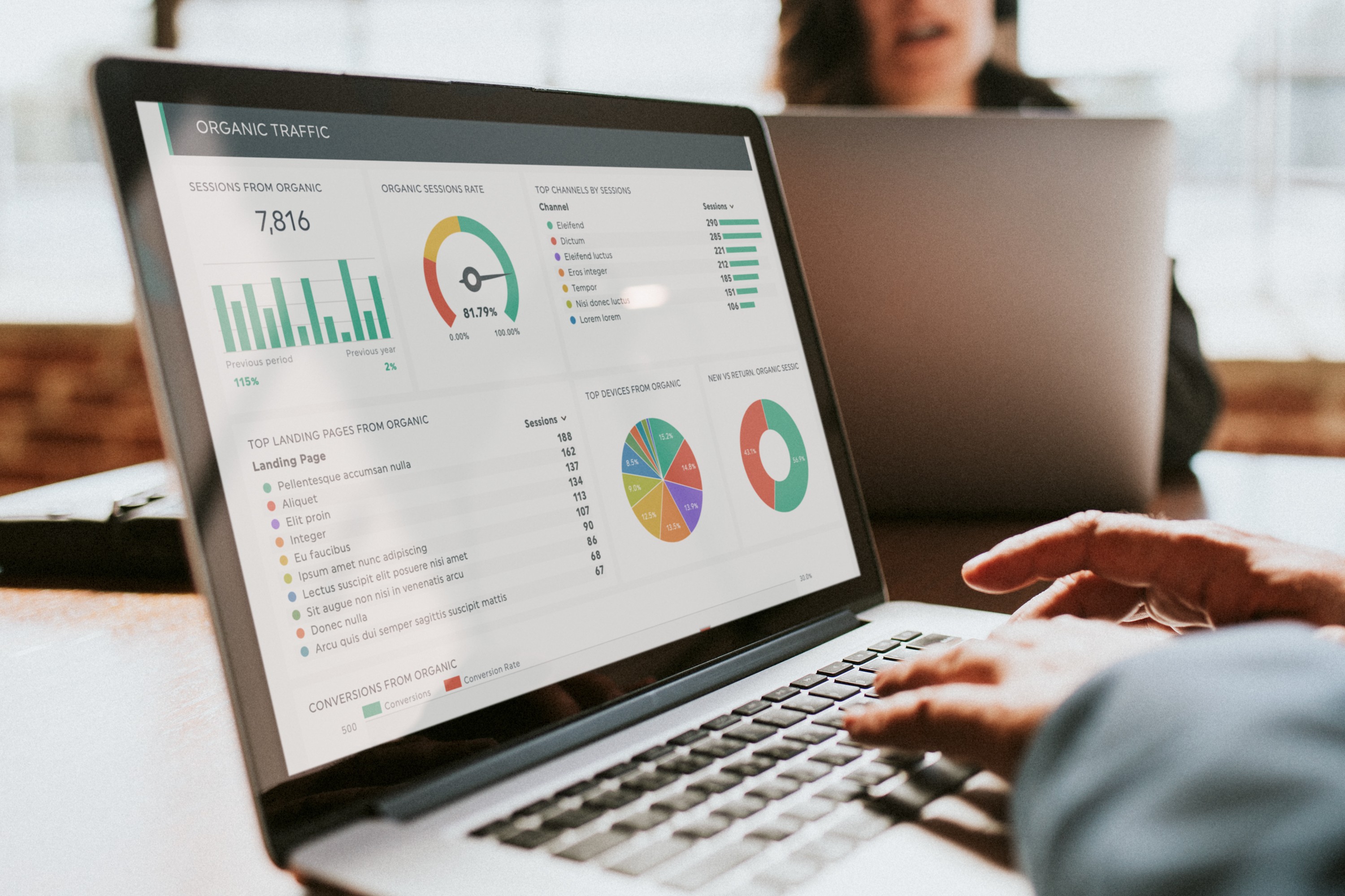 Close-up of a laptop screen with hands typing on the keyboard, displaying a dashboard showing SEO organic traffic results, including graphs and metrics.