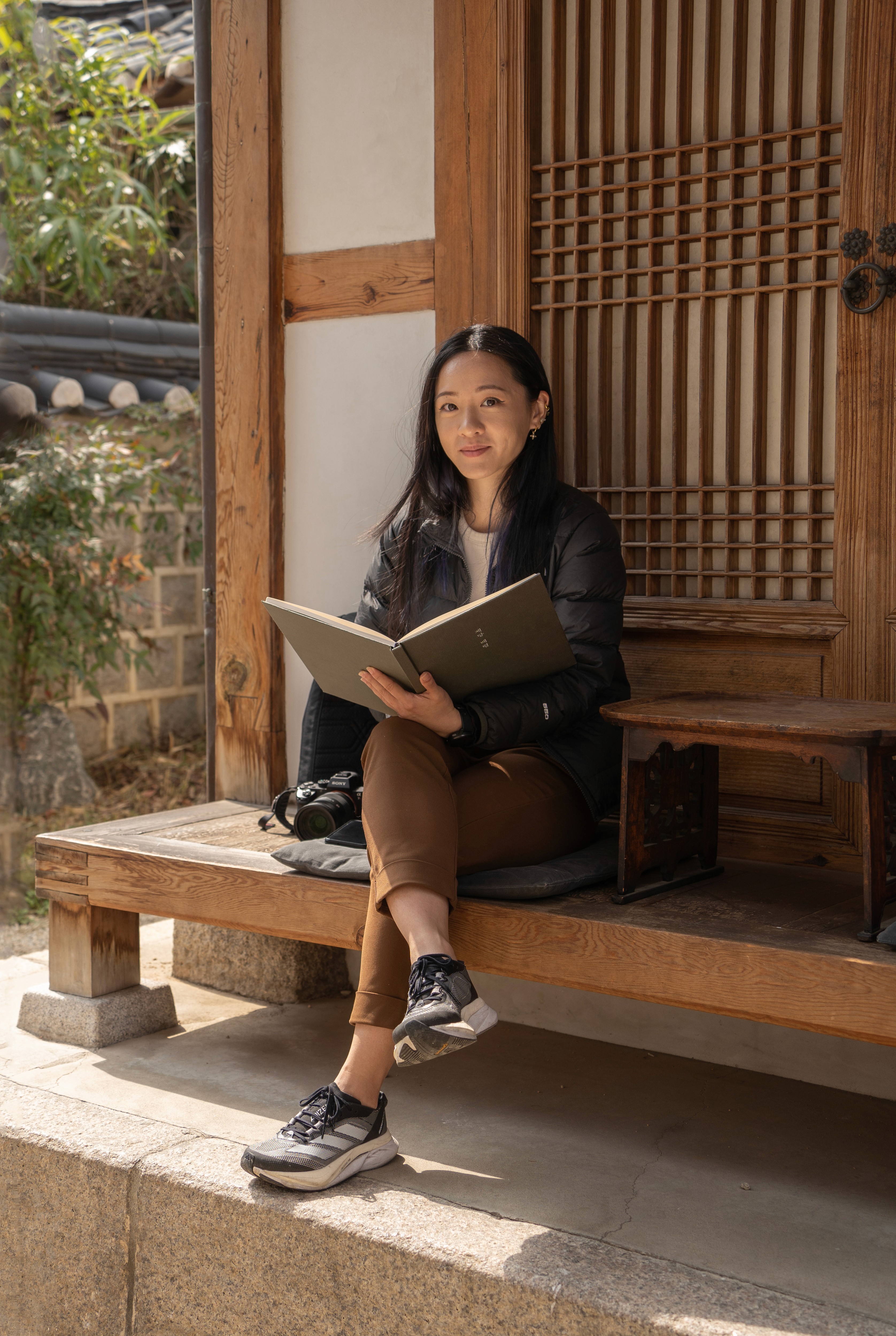 A young person with long, wavy hair sits in front of a plain background, looking directly at the camera.