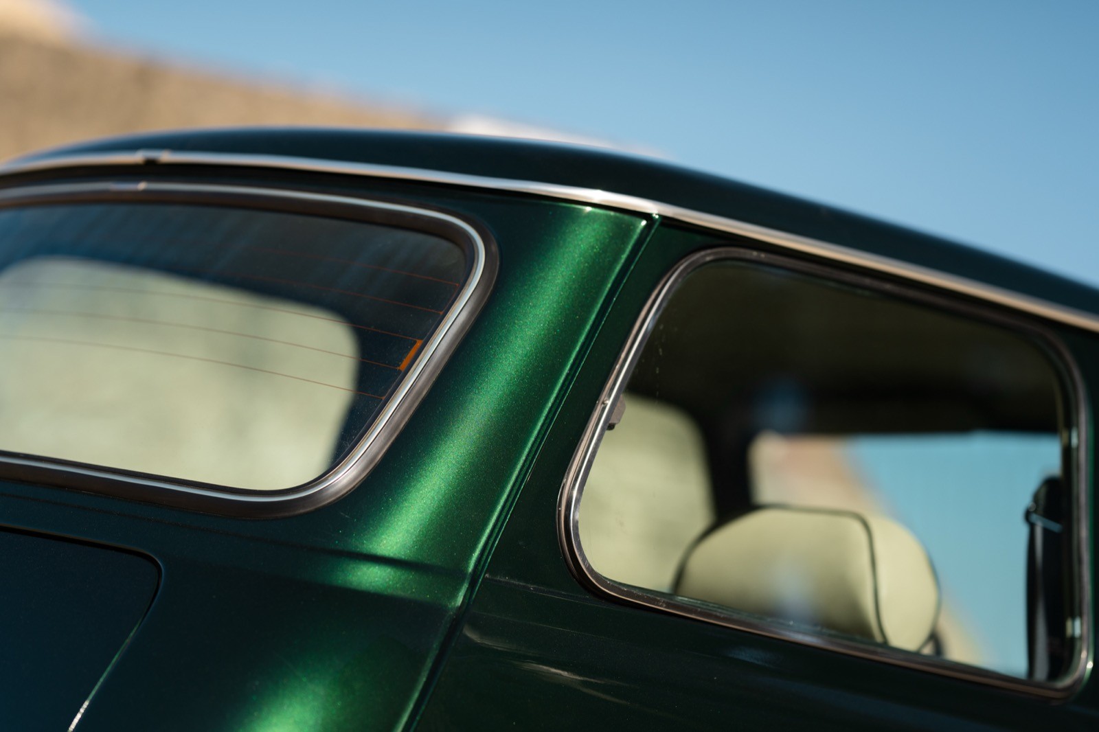 A small, green and black vehicle parked on a sandy surface, with a warm sunset lighting the scene.