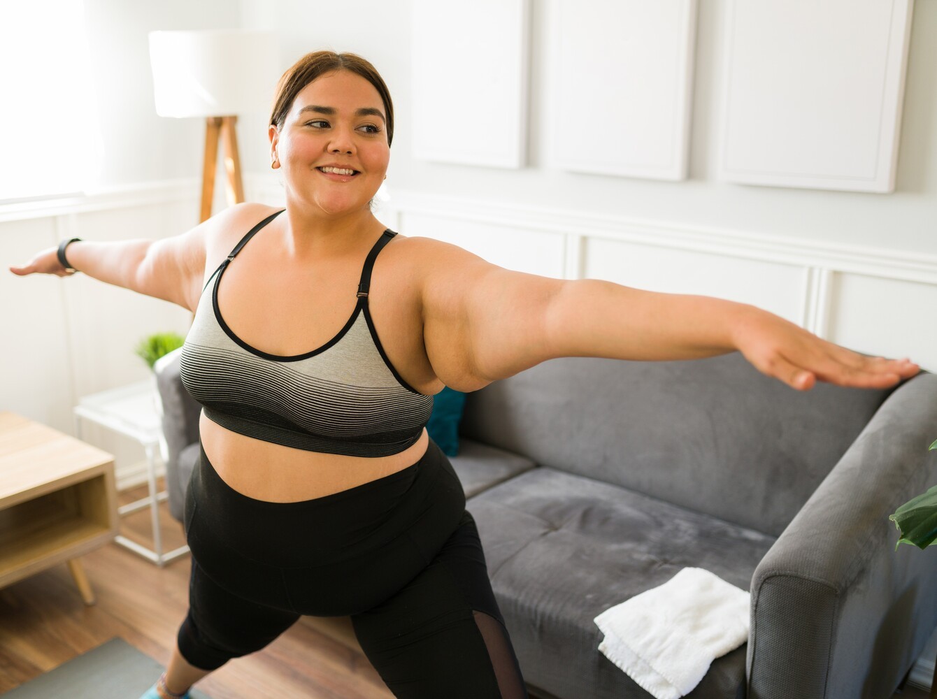 smiling woman enjoying herself as she does yoga to lose weight at home in her living room