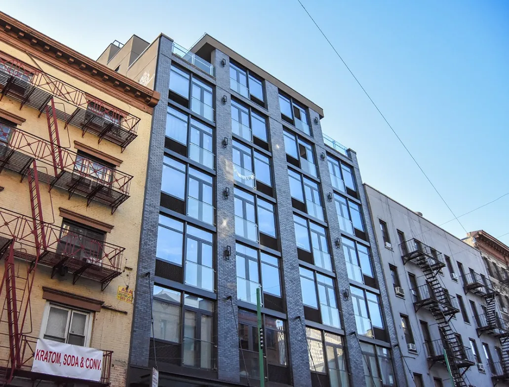 A tall building with numerous windows stands prominently along the street, showcasing modern architecture.