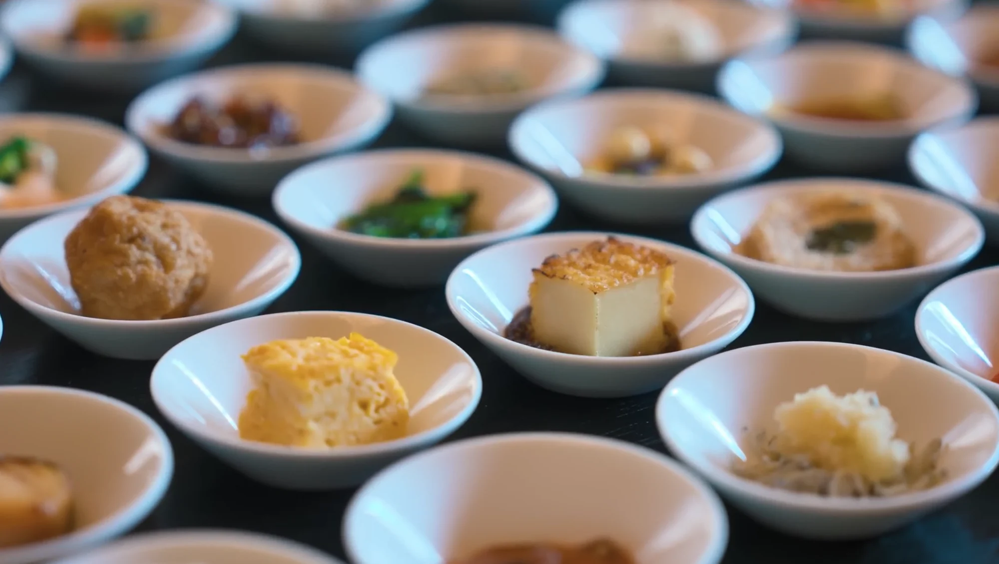 Rows of dozens of small white bowls holding individual ryokan breakfast portions