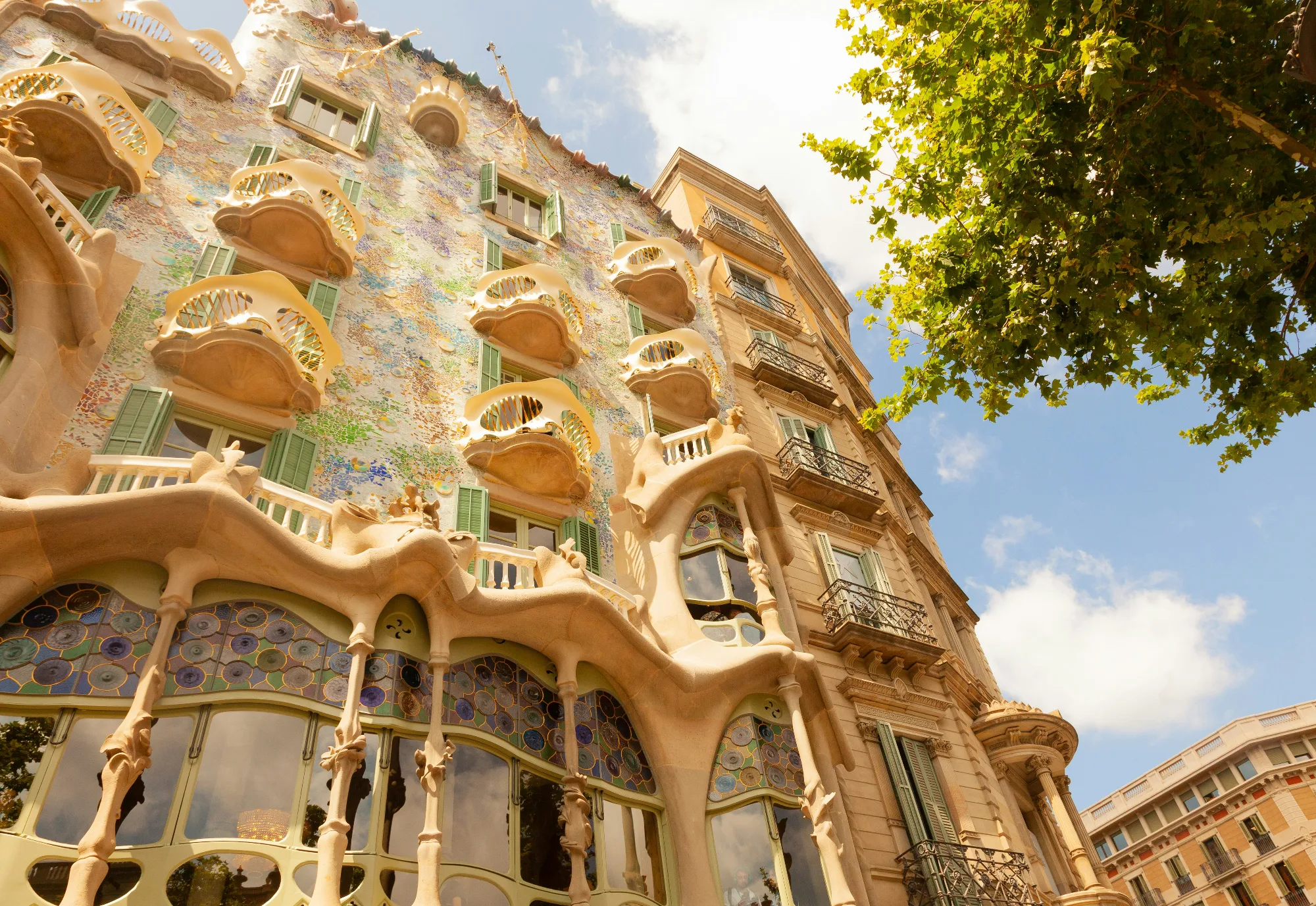 Casa Batlló Barcelona exterior, iconic Gaudi architecture, colorful facade, balconies, and blue sky.