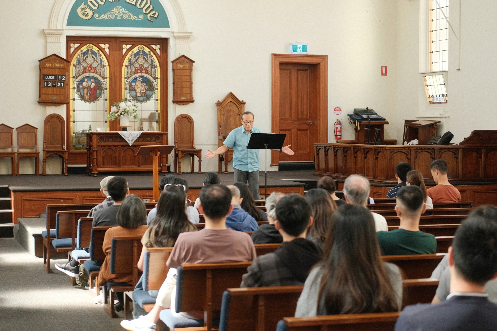 A restaurant interior featuring marble countertops, brown leather chairs, wood-paneled walls, and round pendant lights hanging above a bar set with wine glasses.