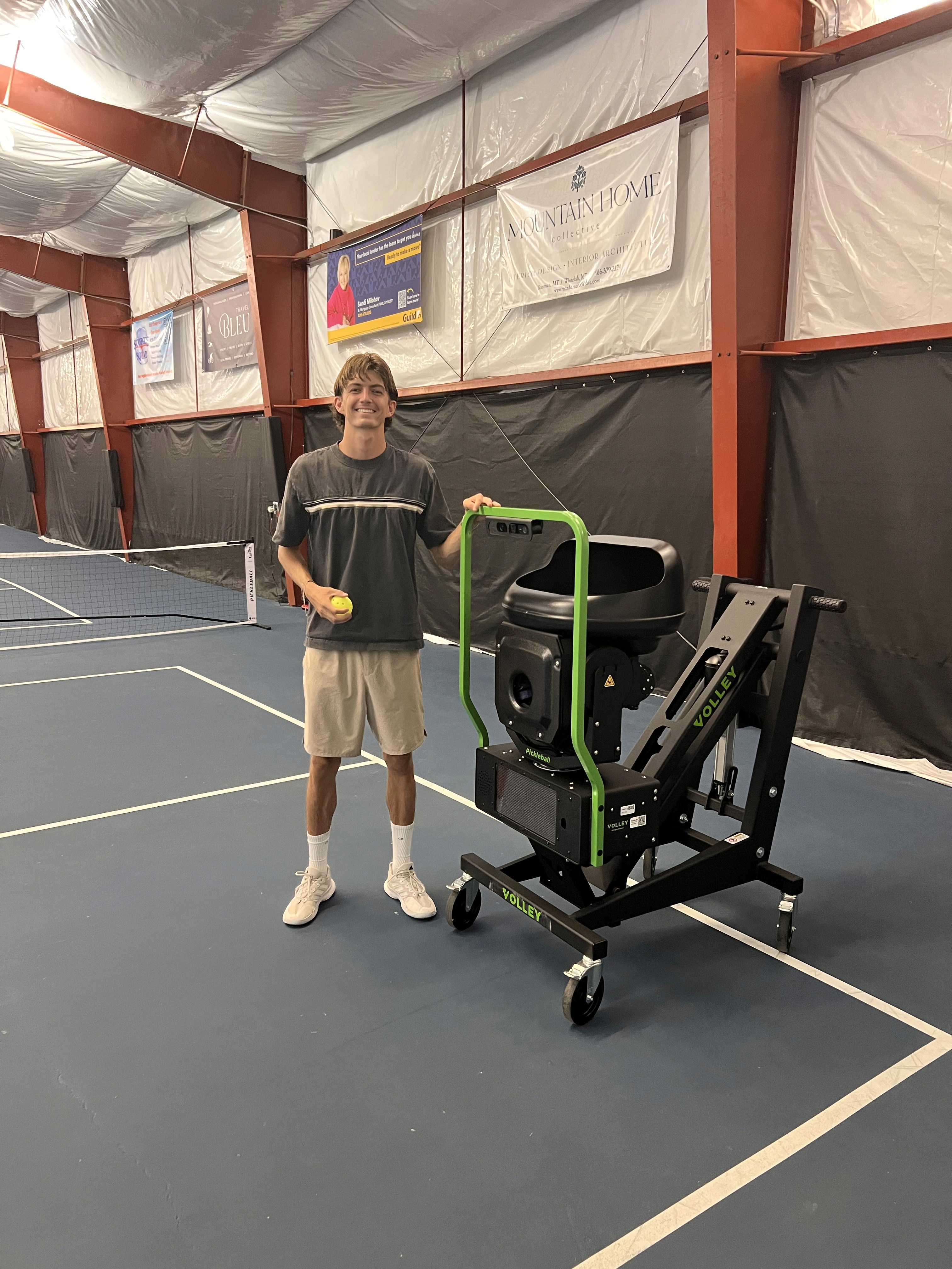 Instructor Harrison Bork smiling beside the ball machine