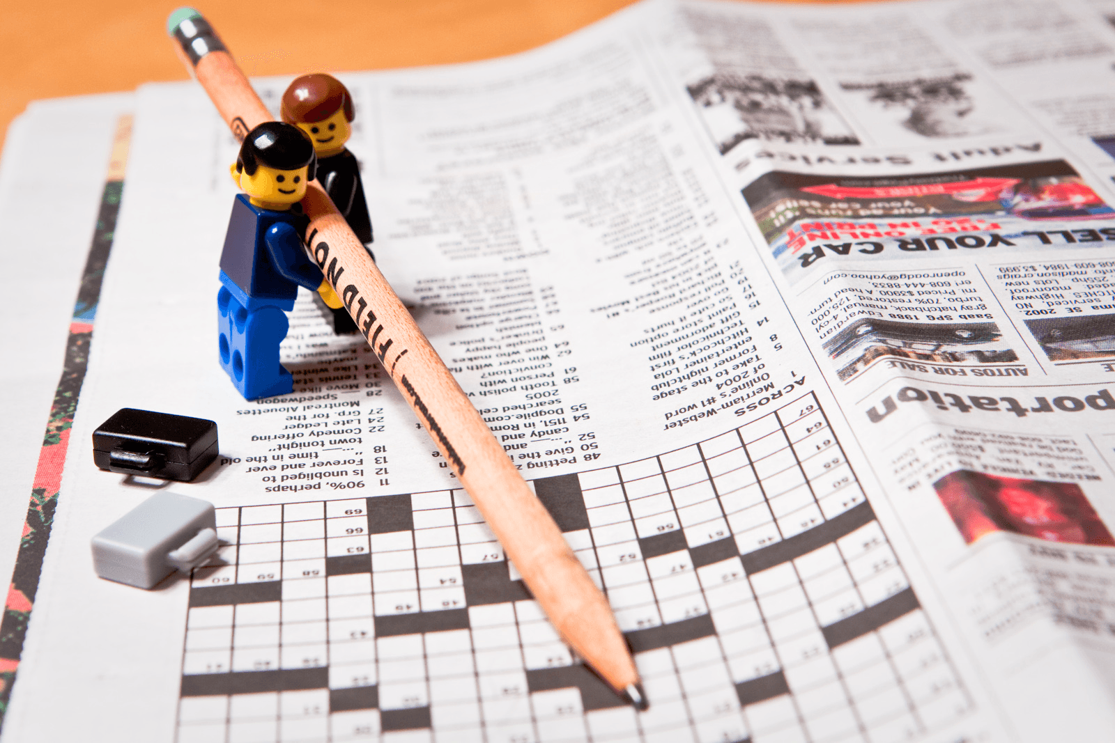 Two Lego figurines solving newspaper crossword puzzle