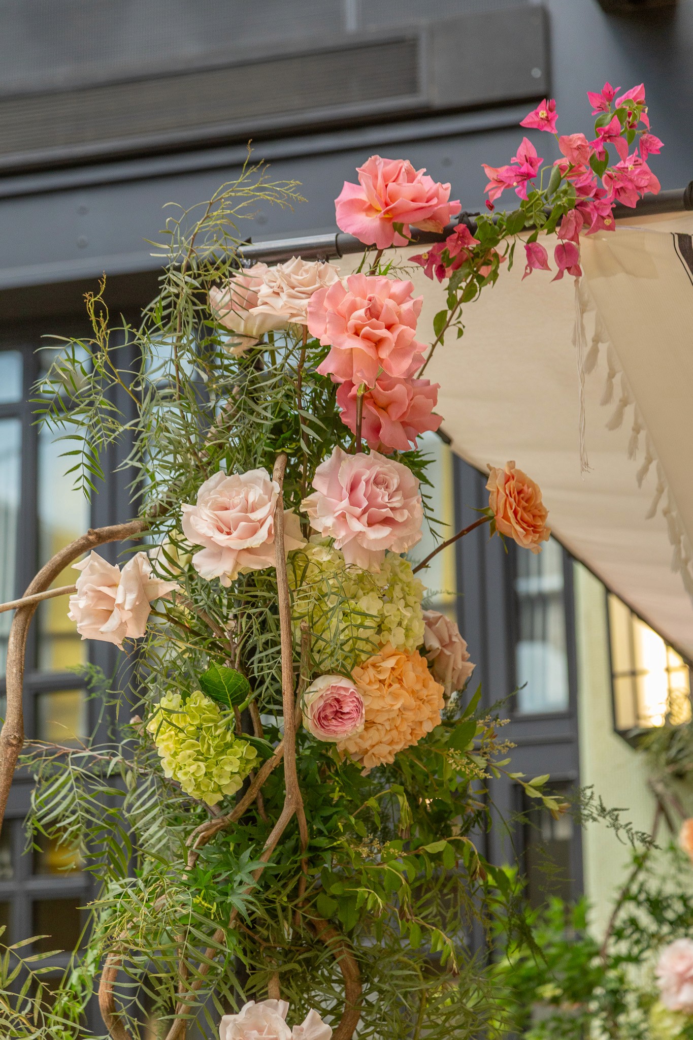 Detalle de arco floral con rosas rosadas, hortensias verdes y ramas de santa rita para boda romántica.