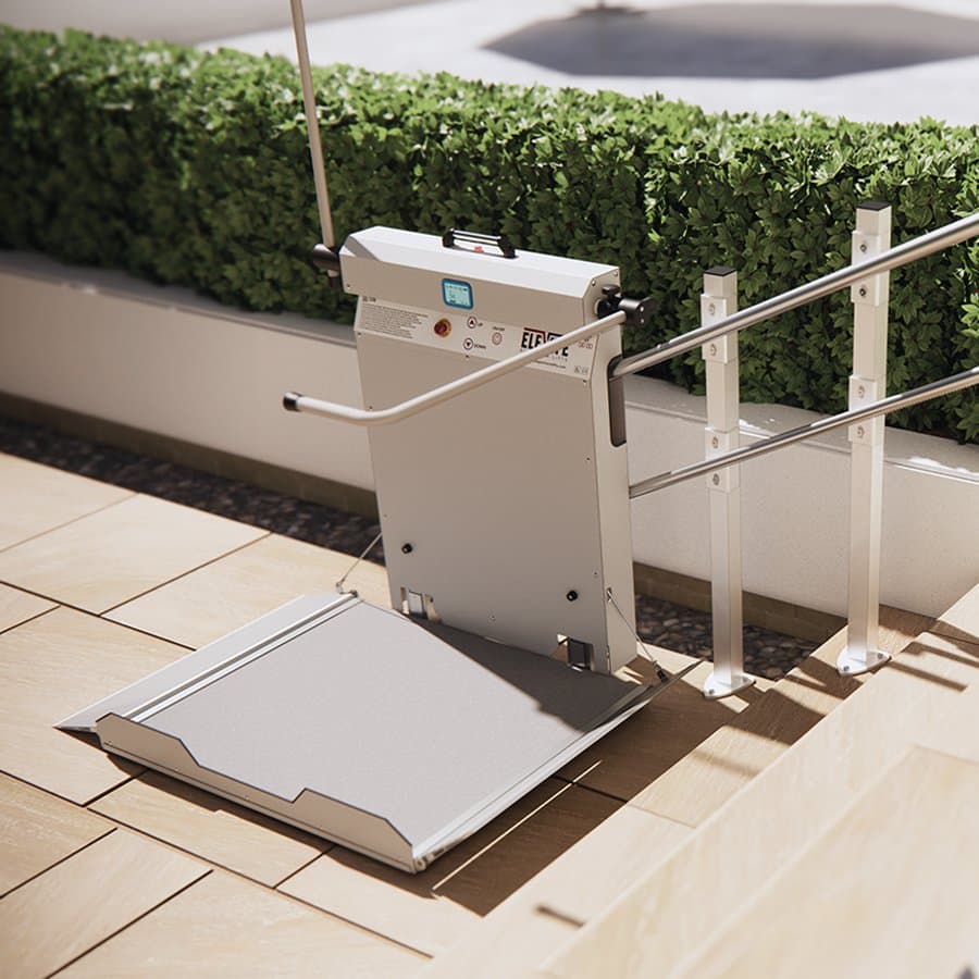 An Elevate Glide inclined platform lift at the lower landing position with the platform deployed, installed on outdoor sandstone steps beside stainless steel handrails at a contemporary commercial or residential property.