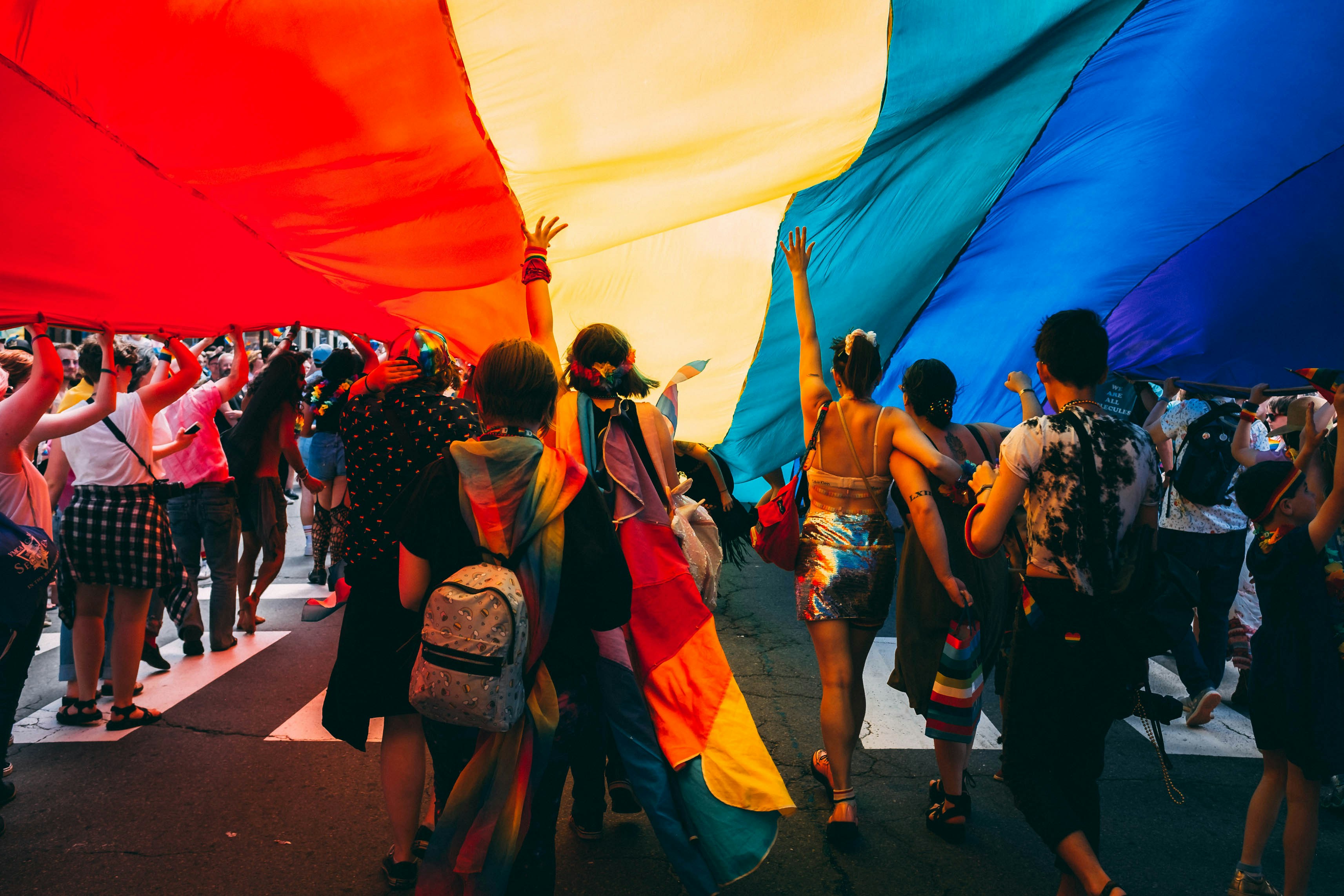 Grupo de personas LGBTIQ+ en una protesta del Día del Orgullo cargando la bandera del arcoíris.