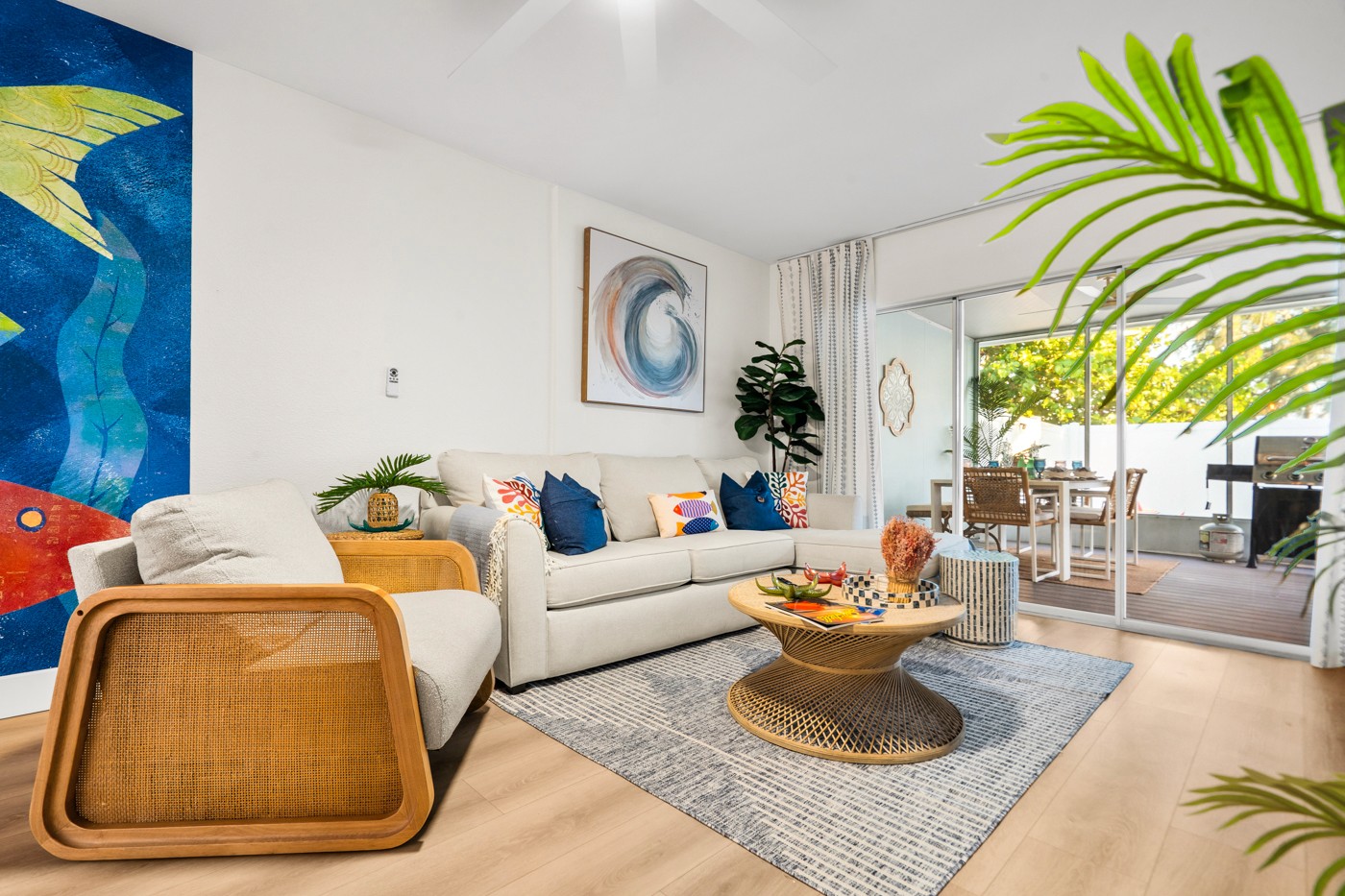 Bright coastal living room in an Anna Maria Island vacation rental with natural textures, artwork and a view to the outdoor living area