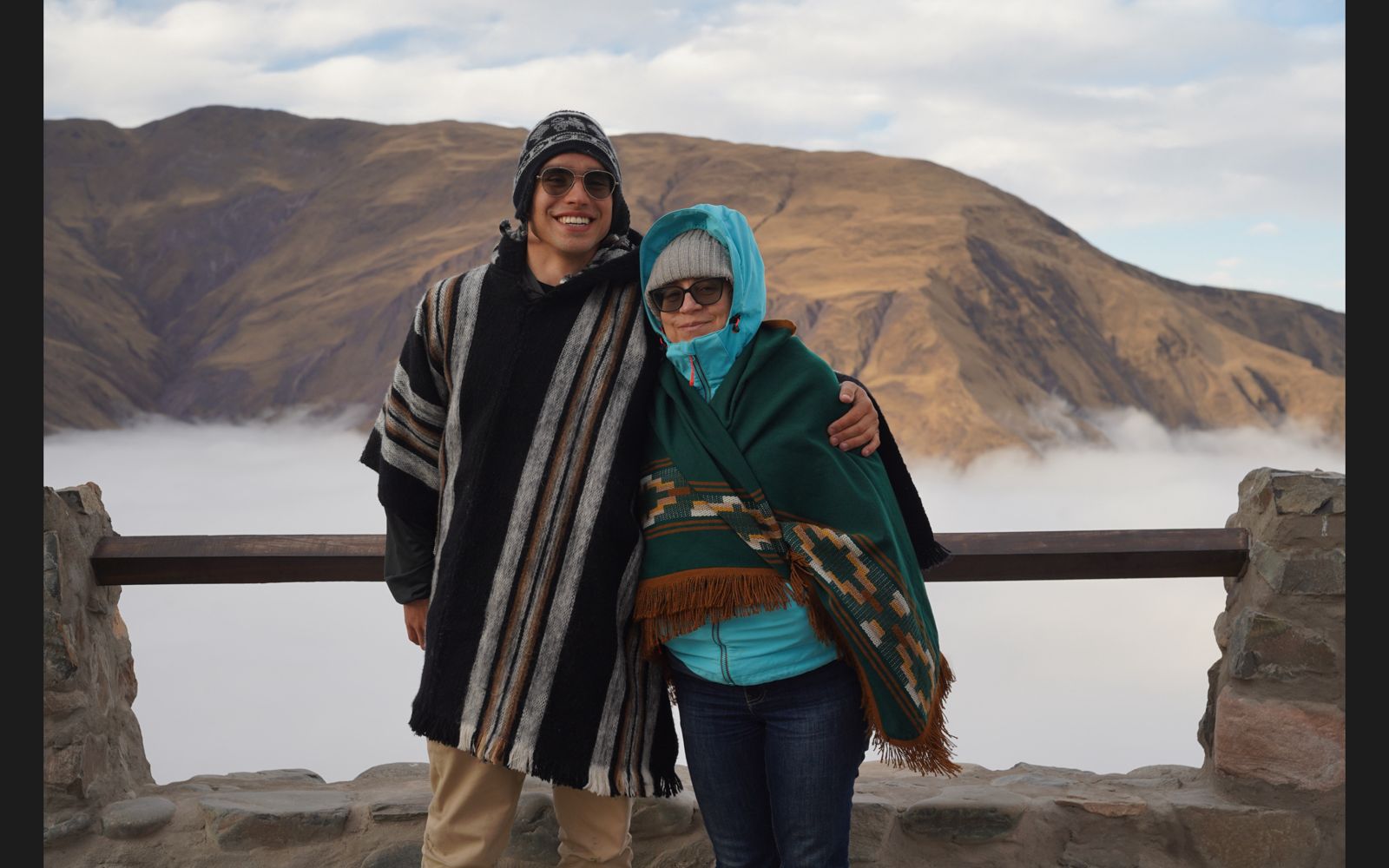Mujer sentada sobre un tronco frente a una cascada doble en un bosque frondoso de Argentina.