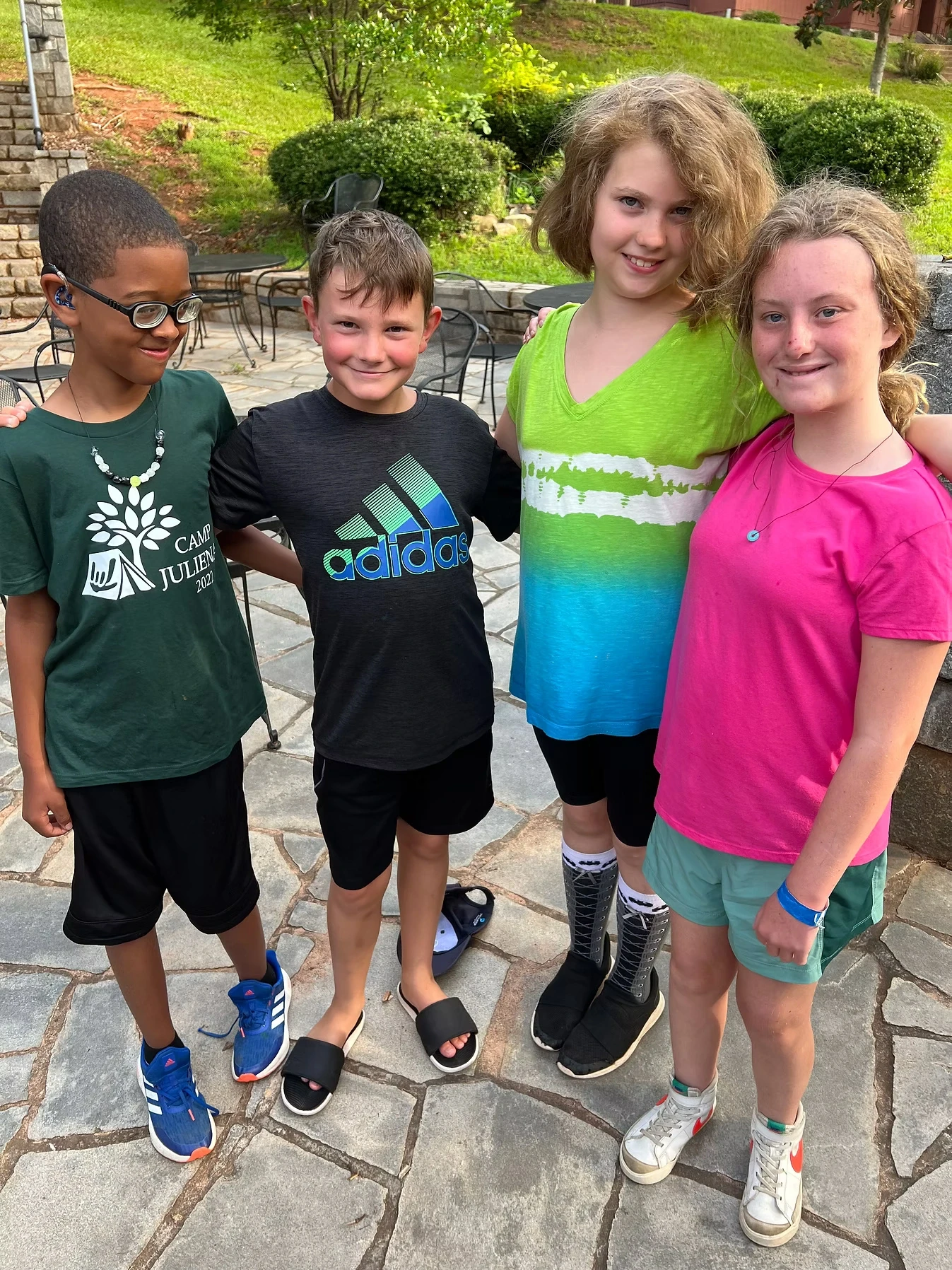 Four campers, two boys and two girls, stand together smiling for a photo.