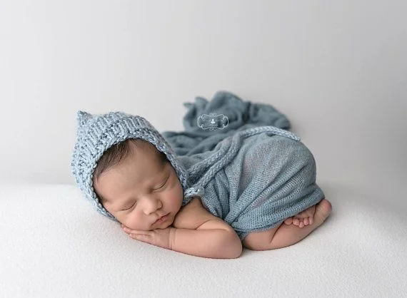 Sleeping newborn in a blue bonnet and wrap