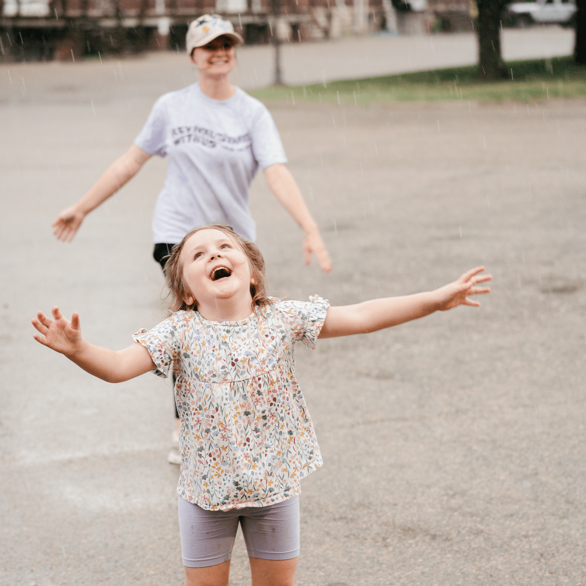 An adult and a kid dancing in the rain.