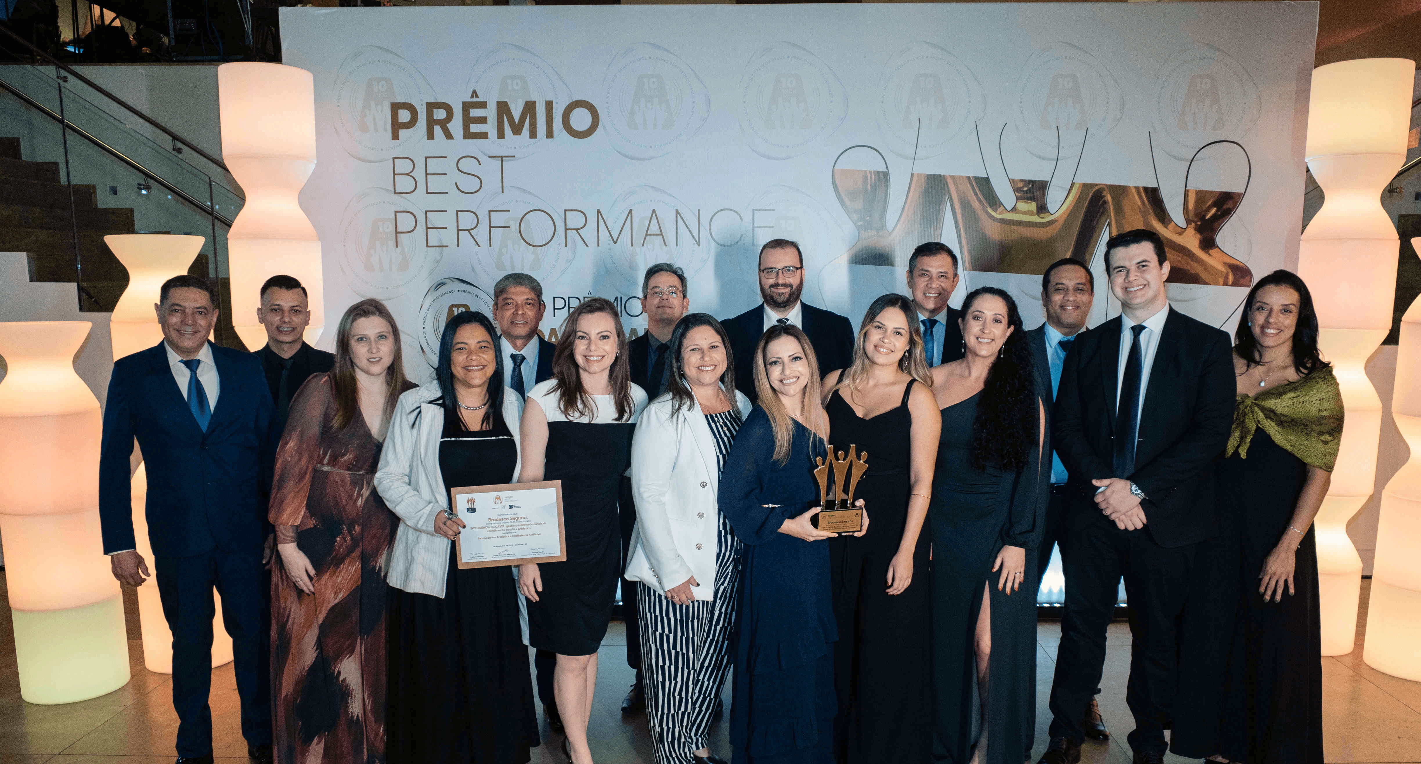 Executivos da Bradesco Seguros posando com troféu ouro e certificado no palco do Prêmio Best Performance 2025