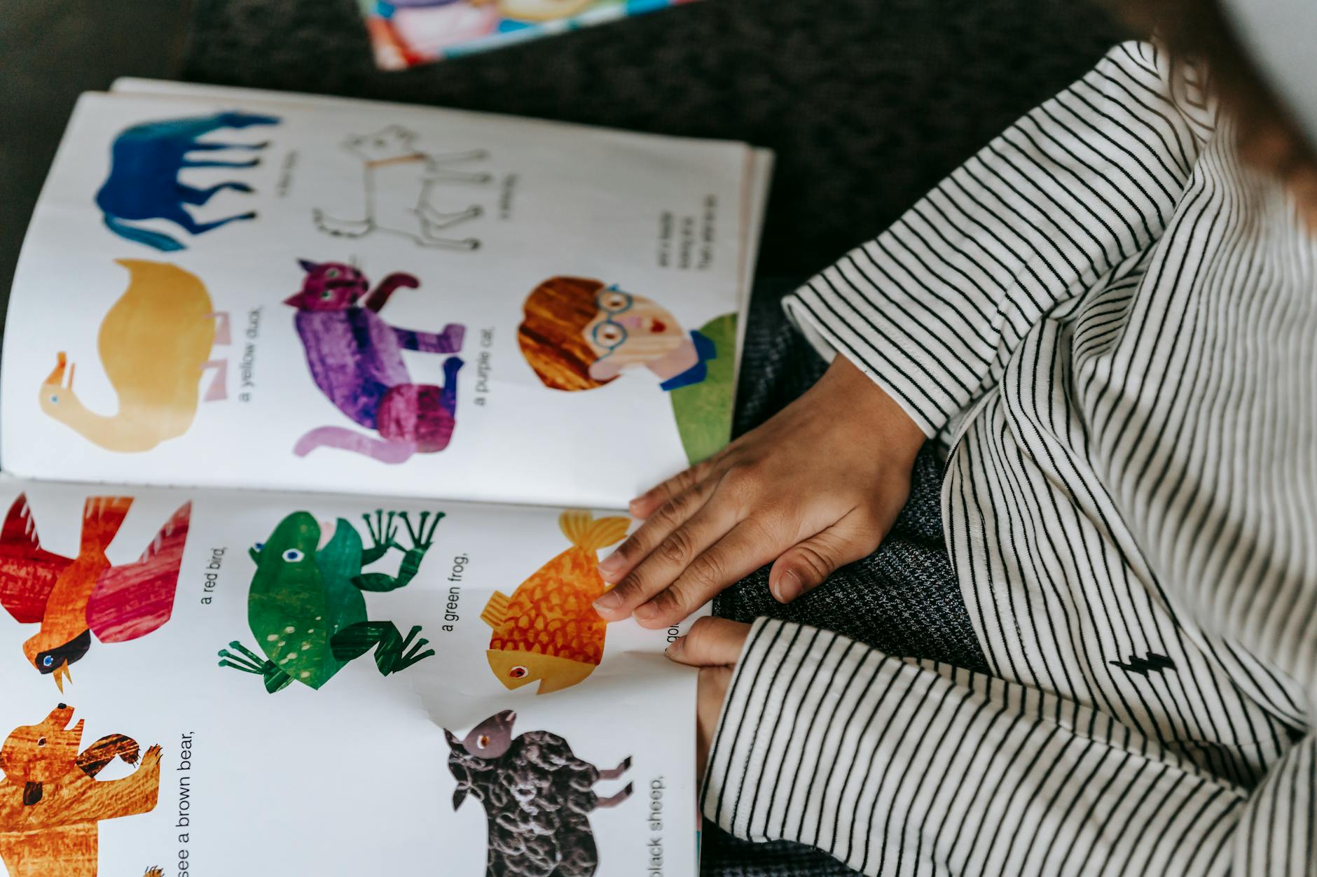 A teacher reading a colorful picture book to a circle of attentive kindergarten students on a classroom rug.