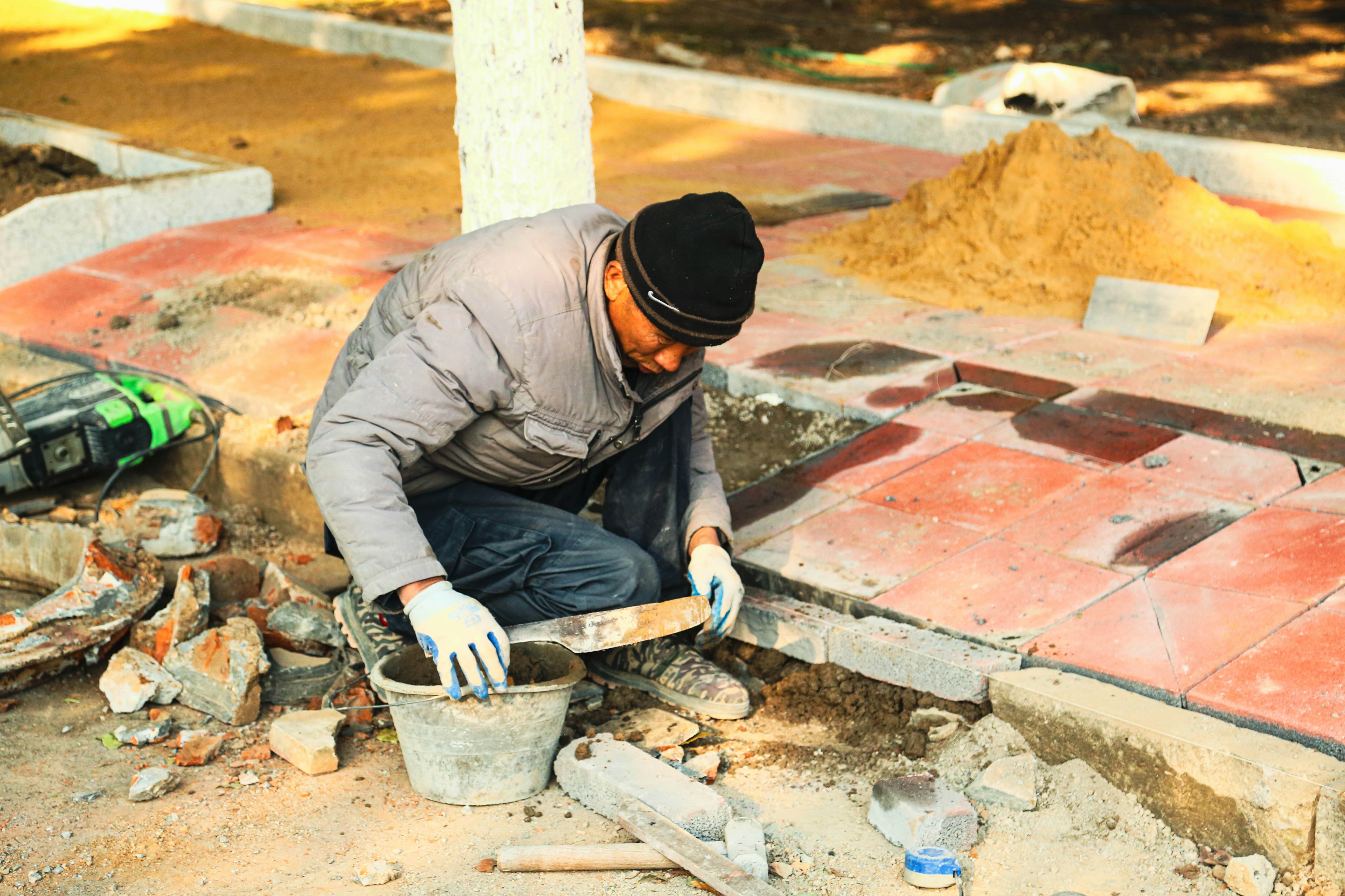 A construction worker is working on the pavement.