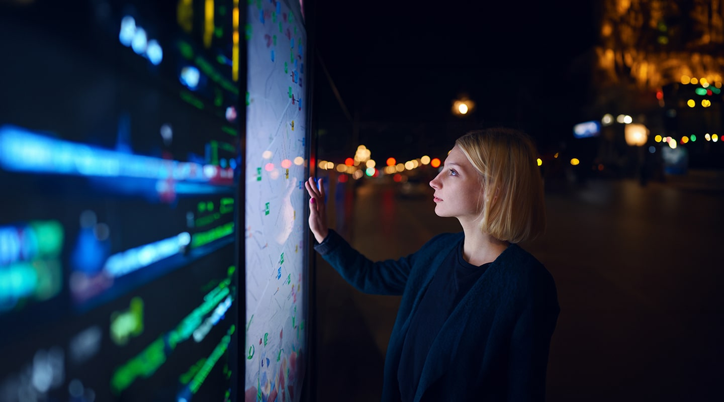 A woman pointing to a digital screen with a city background