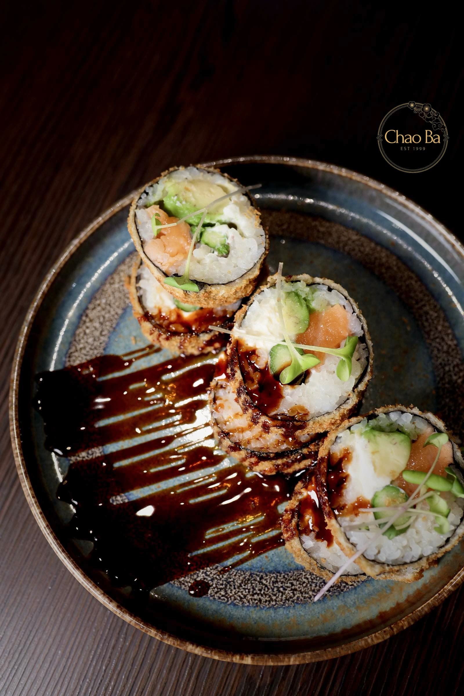 Tempura Sushi Roll mit Avocado und Lachs auf dunklem Teller. Leckeres Sushi Gericht, Japanisches Essen.