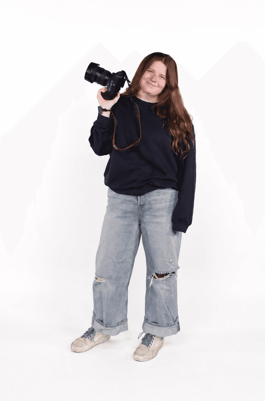 A person with short blonde hair holds a vintage camera.