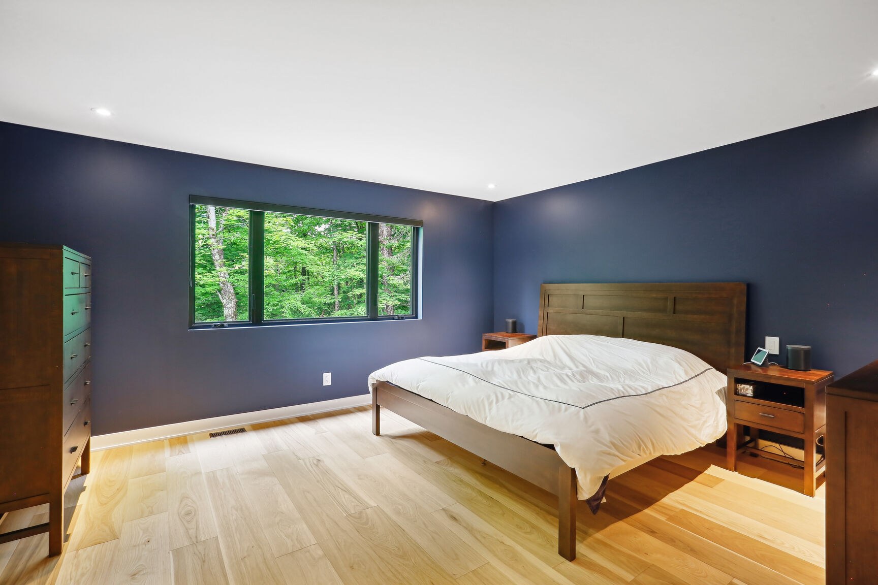 Chambre principale, mur bleu, fenêtre sur le boisé.