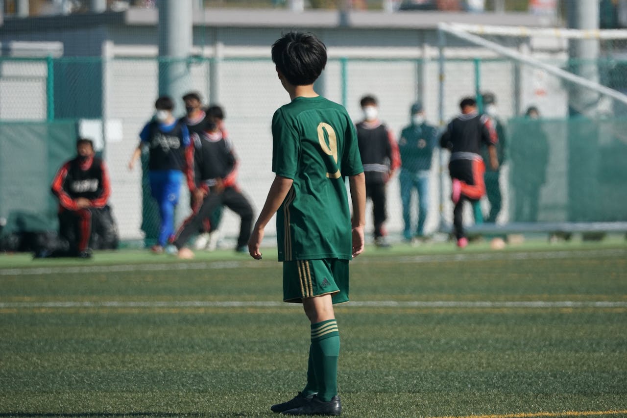 man in white soccer jersey kicking soccer ball on green grass field during daytime