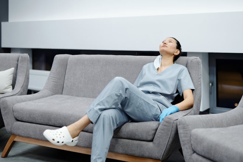 a tired dentist sits on an office couch