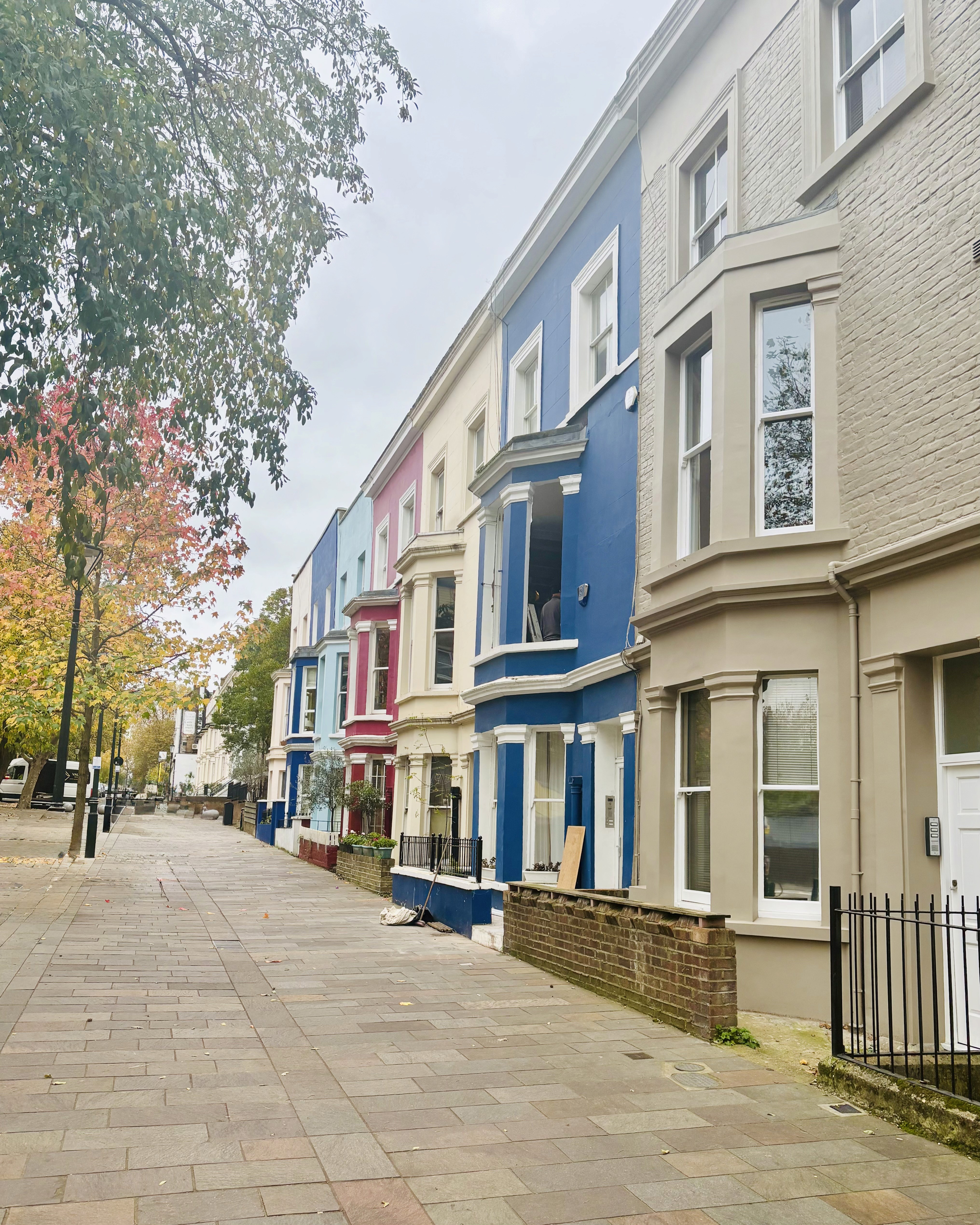 Row of colorful townhouses on a quiet street with autumn trees