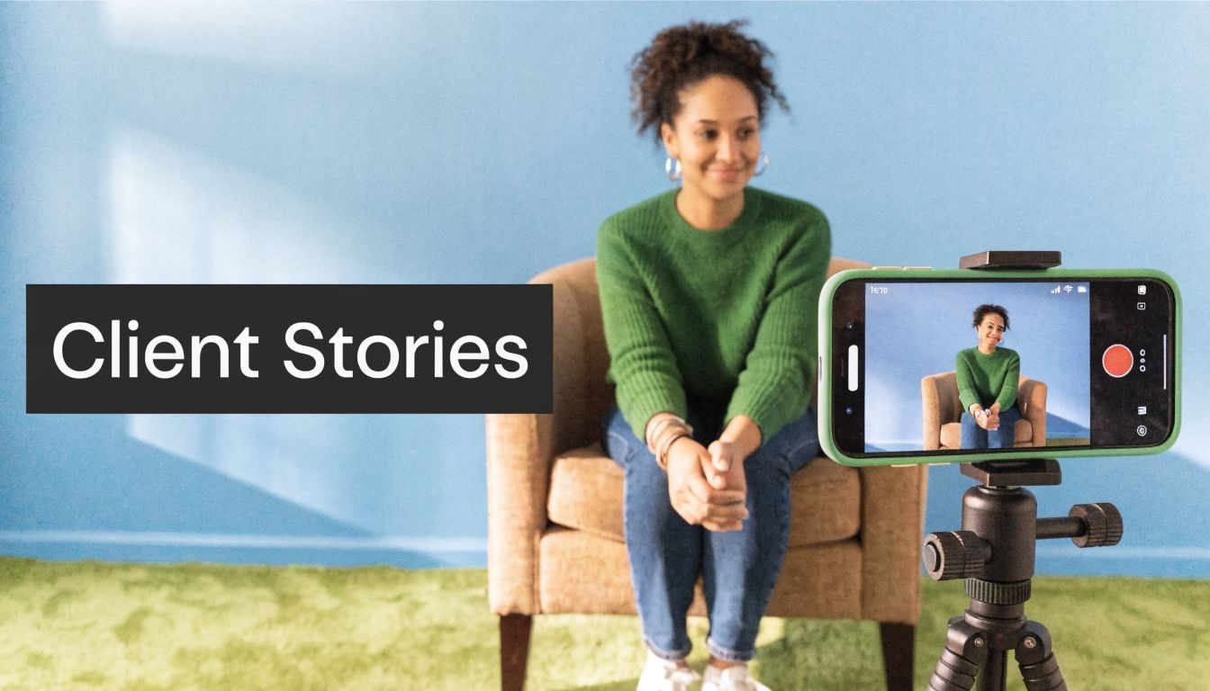 A woman in a green sweater sits in a chair being recorded by a smartphone on a tripod.