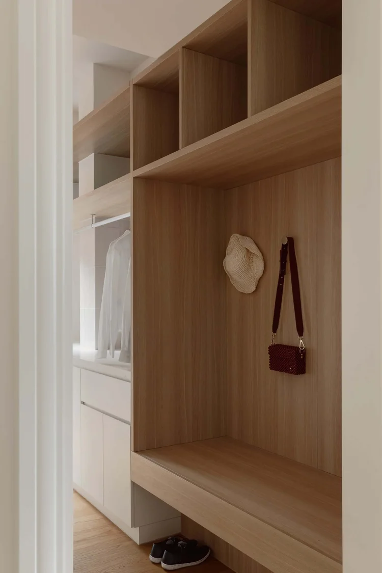 Modern wooden closet with white shirt hanging, organized storage space, and accessories.