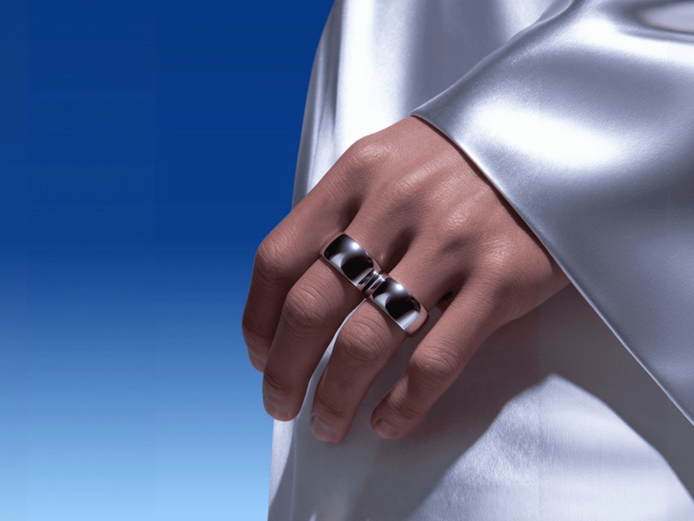 A close-up of a hand wearing multiple decorative rings against a blue background.