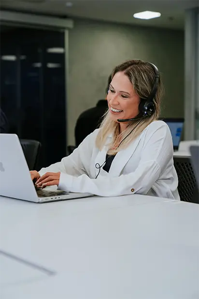 Duas pessoas em um escritório moderno analisando a situação fiscal no computador, com gráficos de desempenho ao fundo, garantindo a conformidade da empresa.