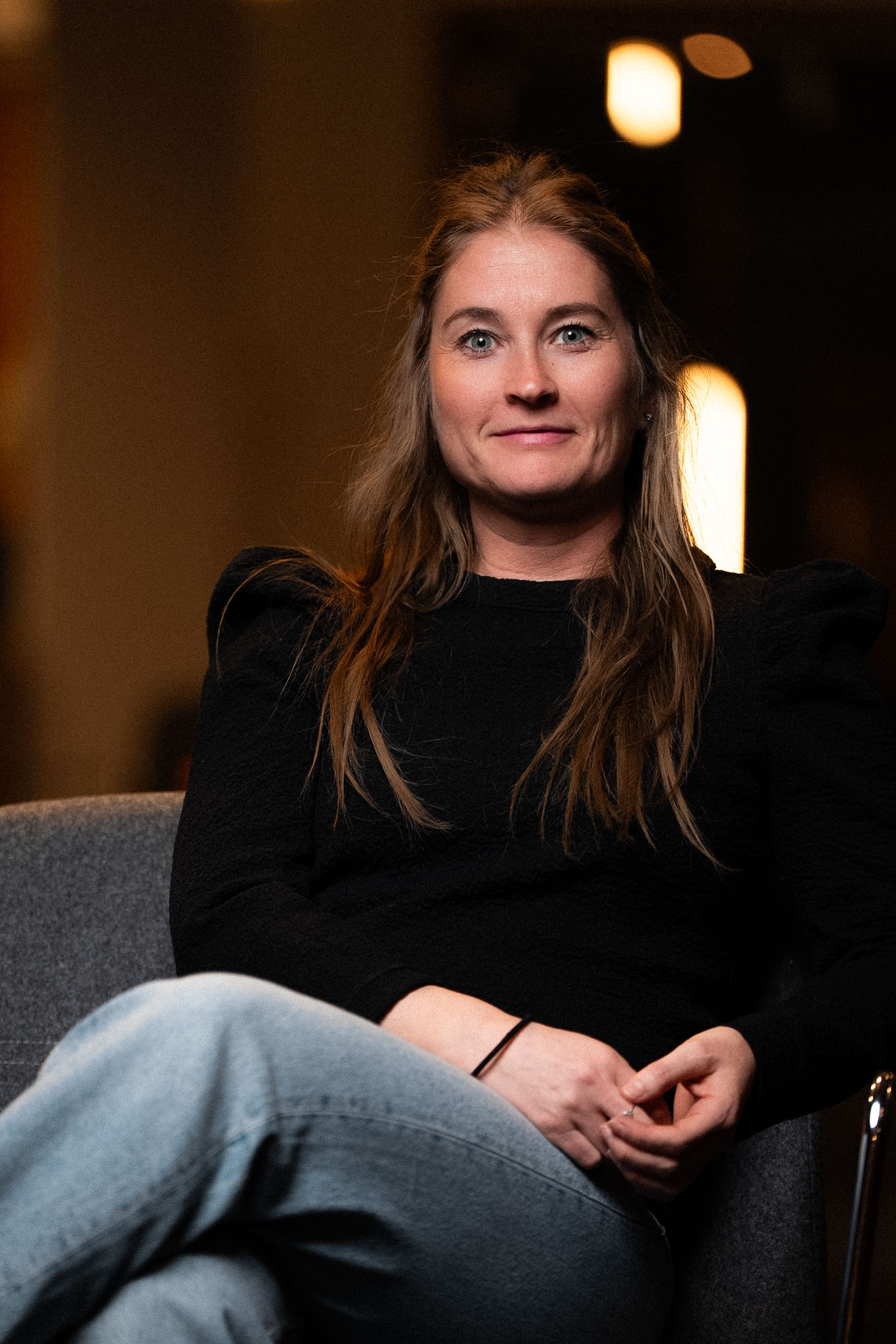 Several male athletes sprint down a track lane during a competitive race with stadium seating in the background.