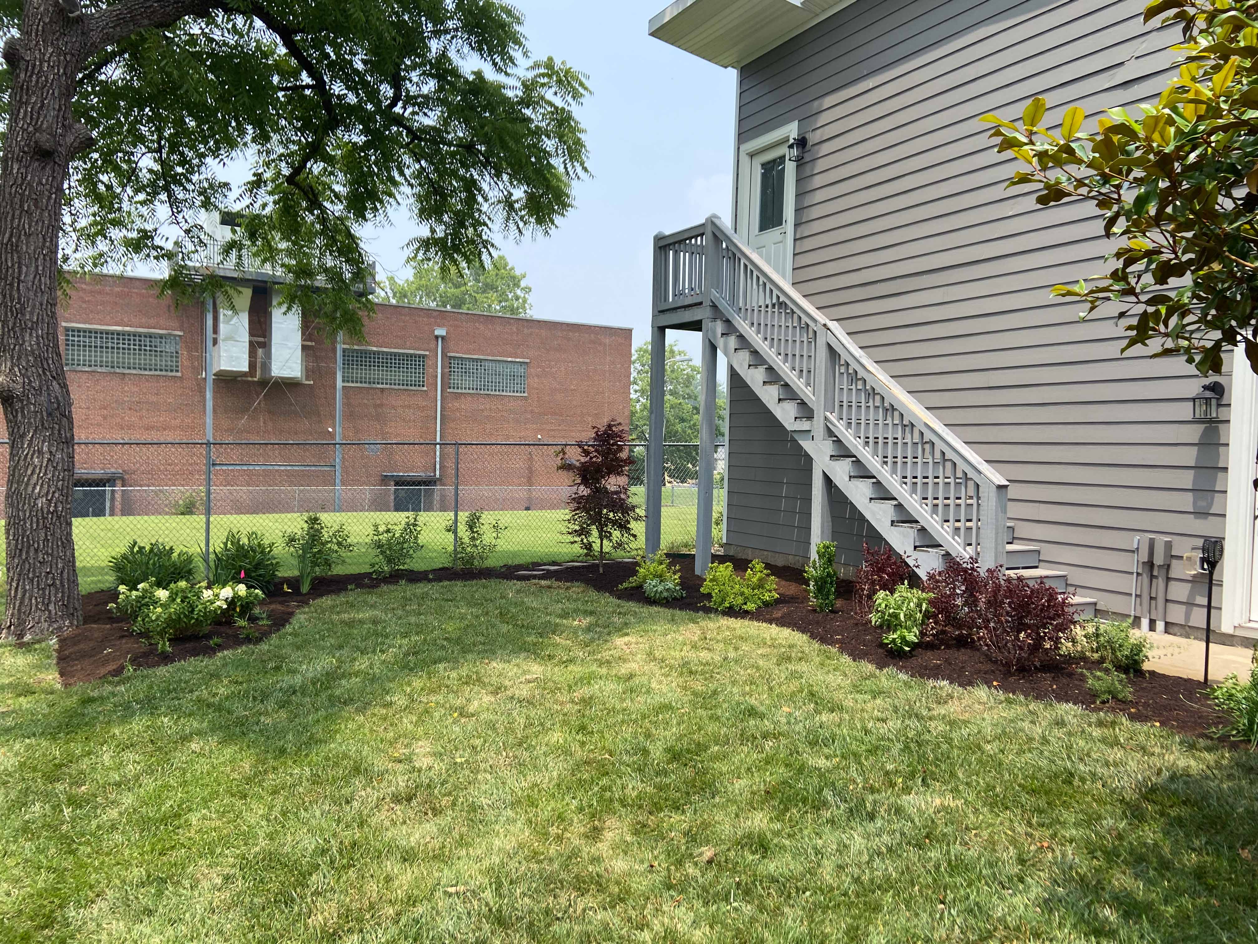 Backyard with mulched bed and shrubs under staircase.