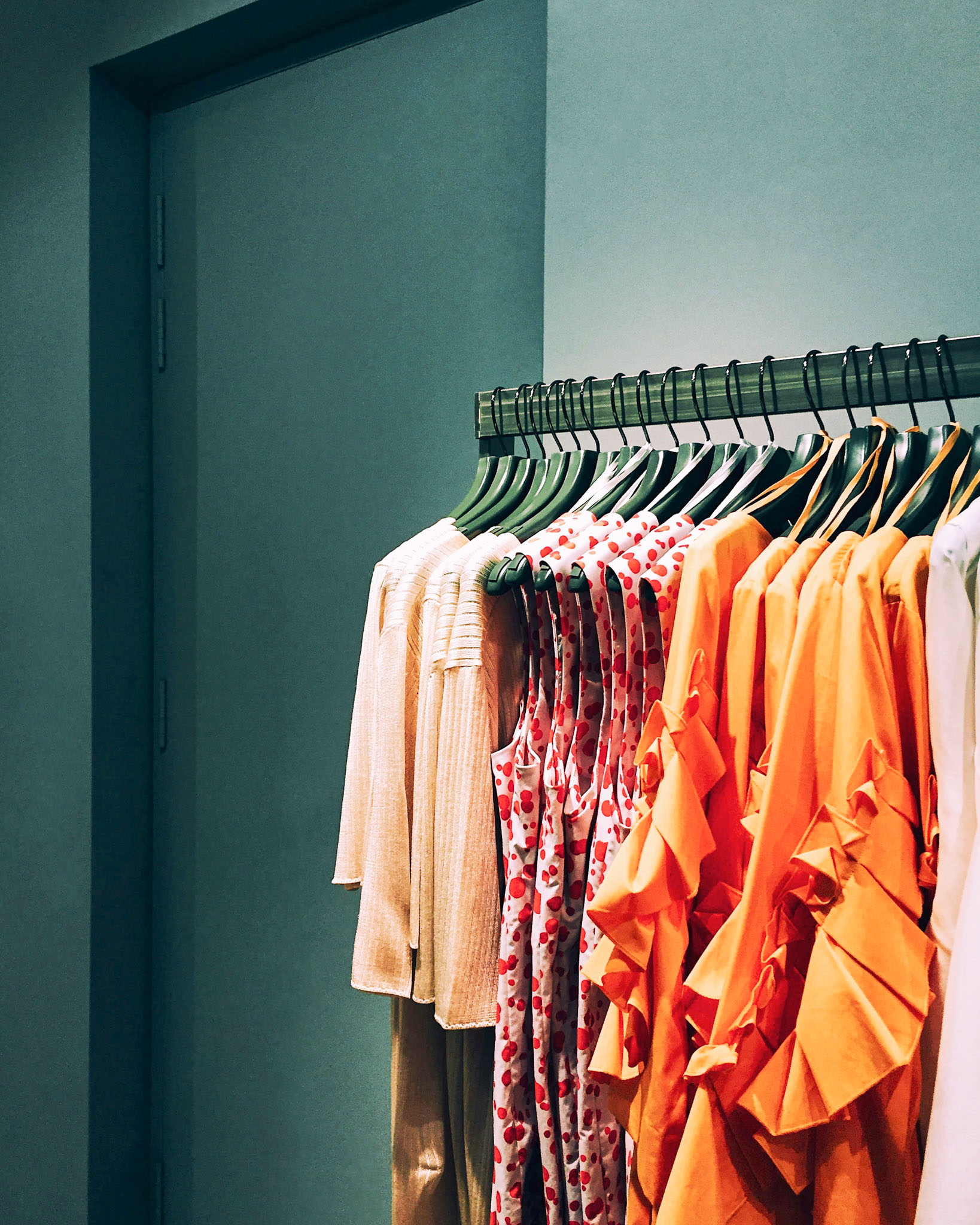 Farbenfrohe Damenbekleidung ordentlich auf Kleiderbügeln in einer stilvollen Ladenumgebung. Die Fashion-Branche vereint Ästhetik, Schnelligkeit und professionelle Warenpräsentation.
