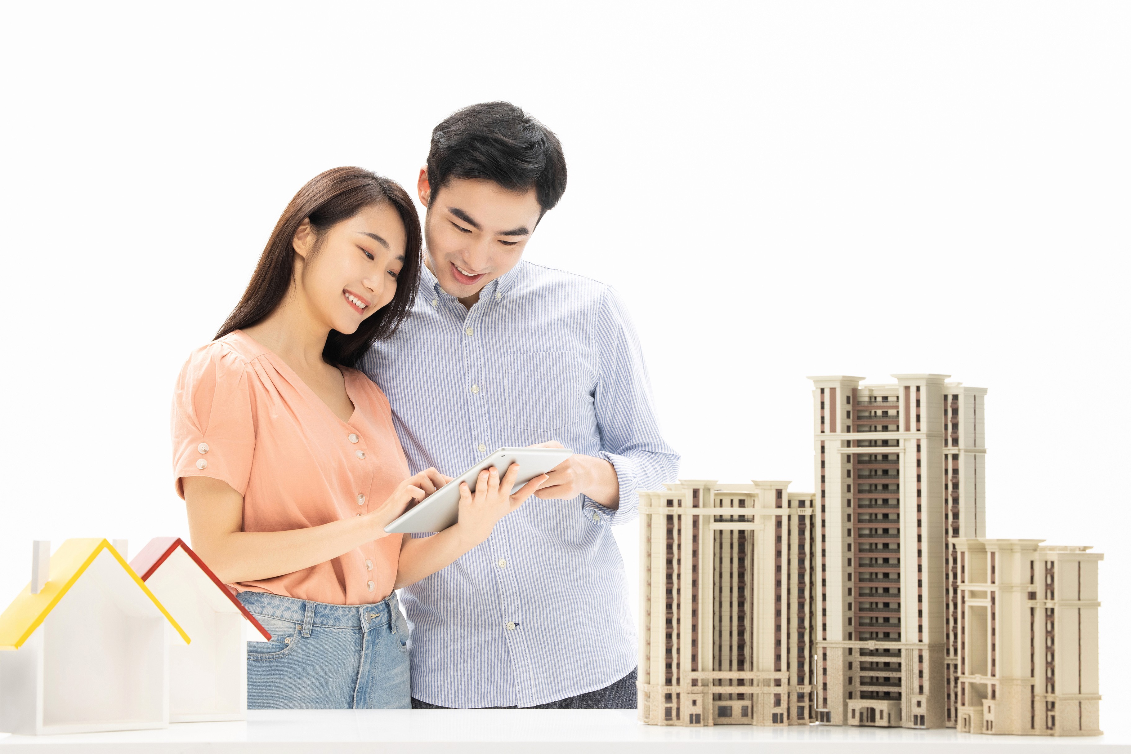 Happy couple looking at a miniature model high-rise building, representing investment advisory and consultation services for Cambodian property buyers.