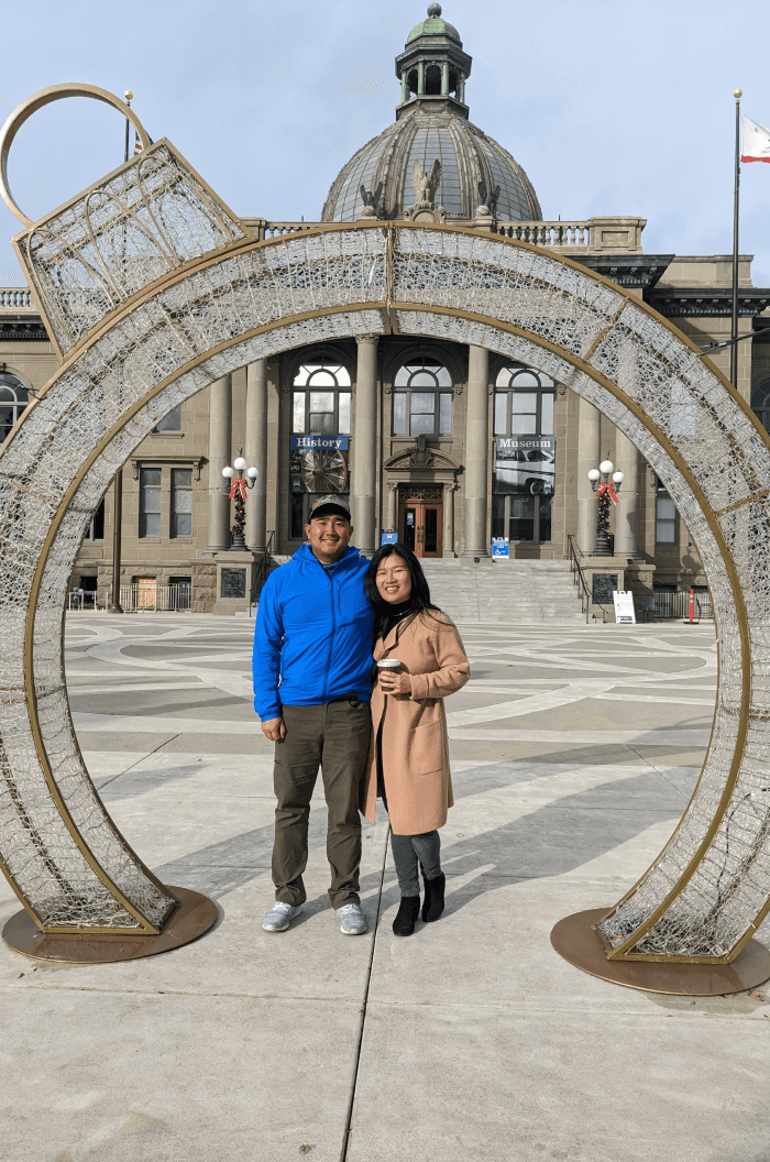 Close-up of two hands gently clasped, one wearing a sparkling engagement ring. The soft lighting and pastel nails evoke a sense of romance and intimacy.