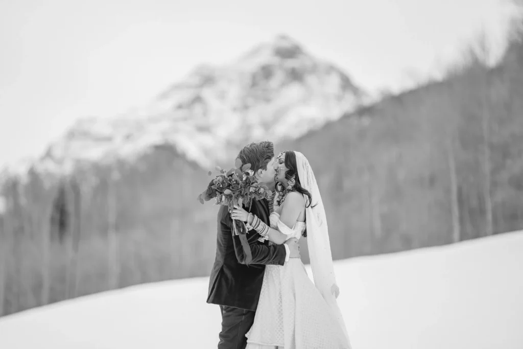 Bride and groom kissing in snowy meadow during T-Lazy 7 elopement Aspen mountains