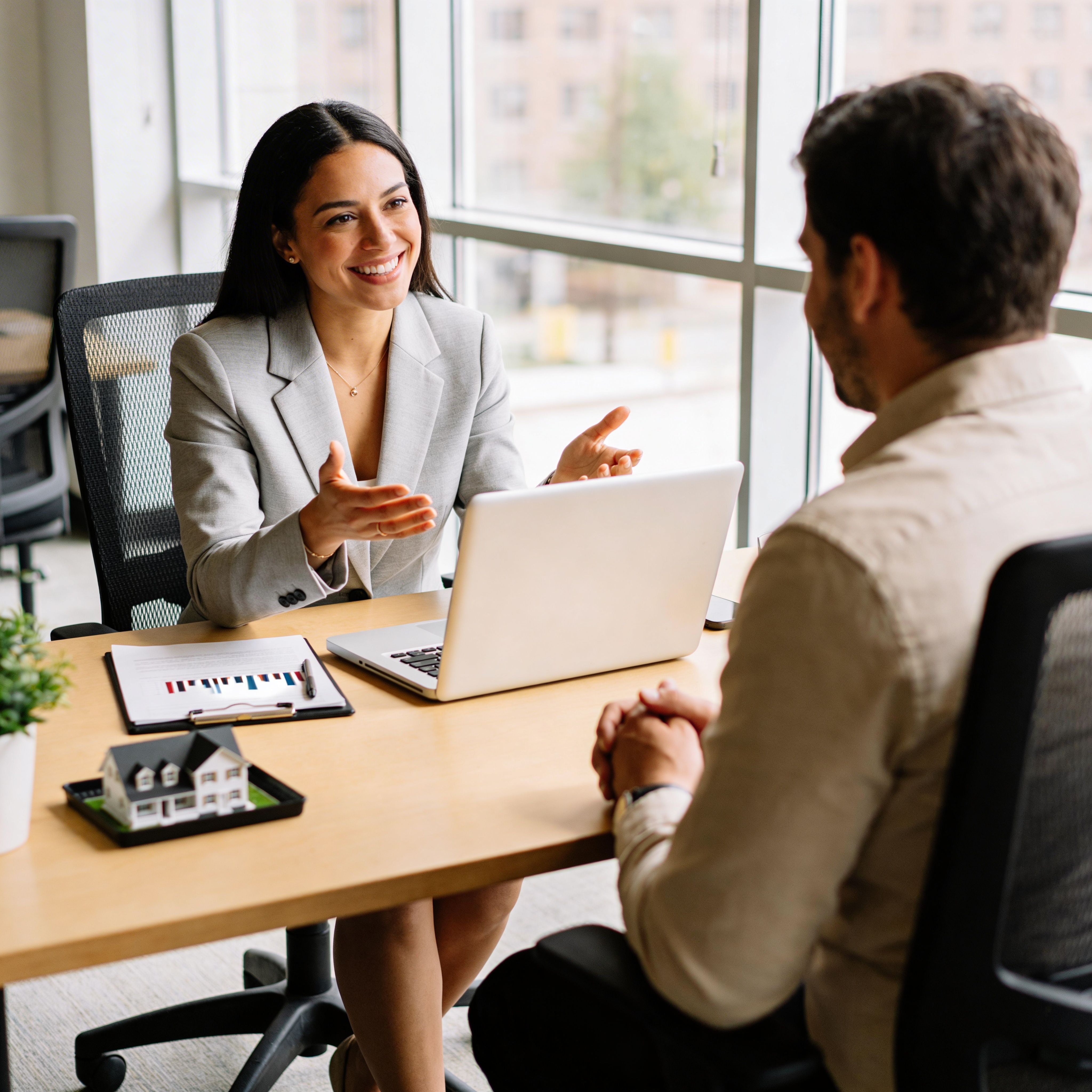 Professional business consultation meeting with a real estate advisor discussing property details with a client in a modern office setting