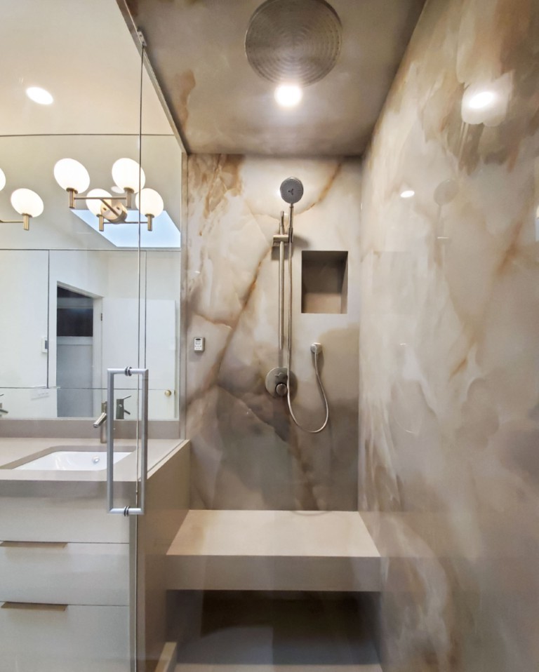 Image of Luxury primary ensuite bathroom with marble walls, built-in shower bench, and modern fixtures by KHD Homes.