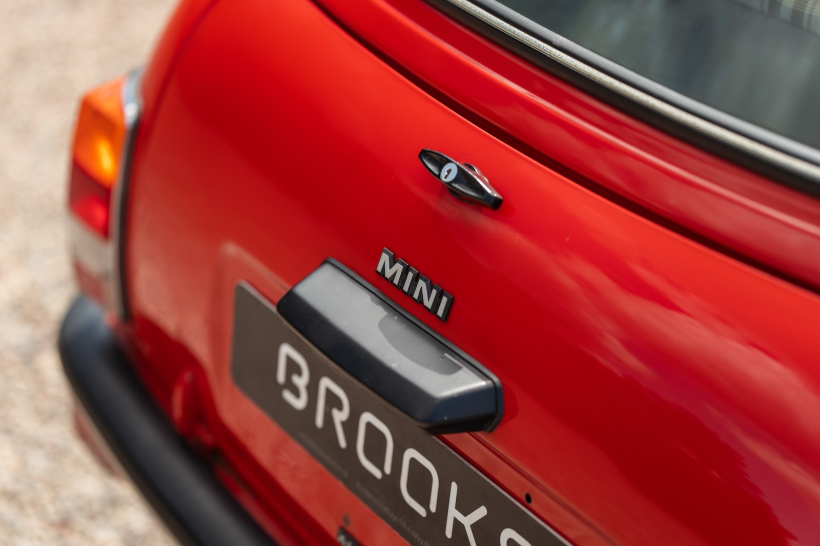 Close-up of the rear of a red car, featuring the handle and part of the license plate area.