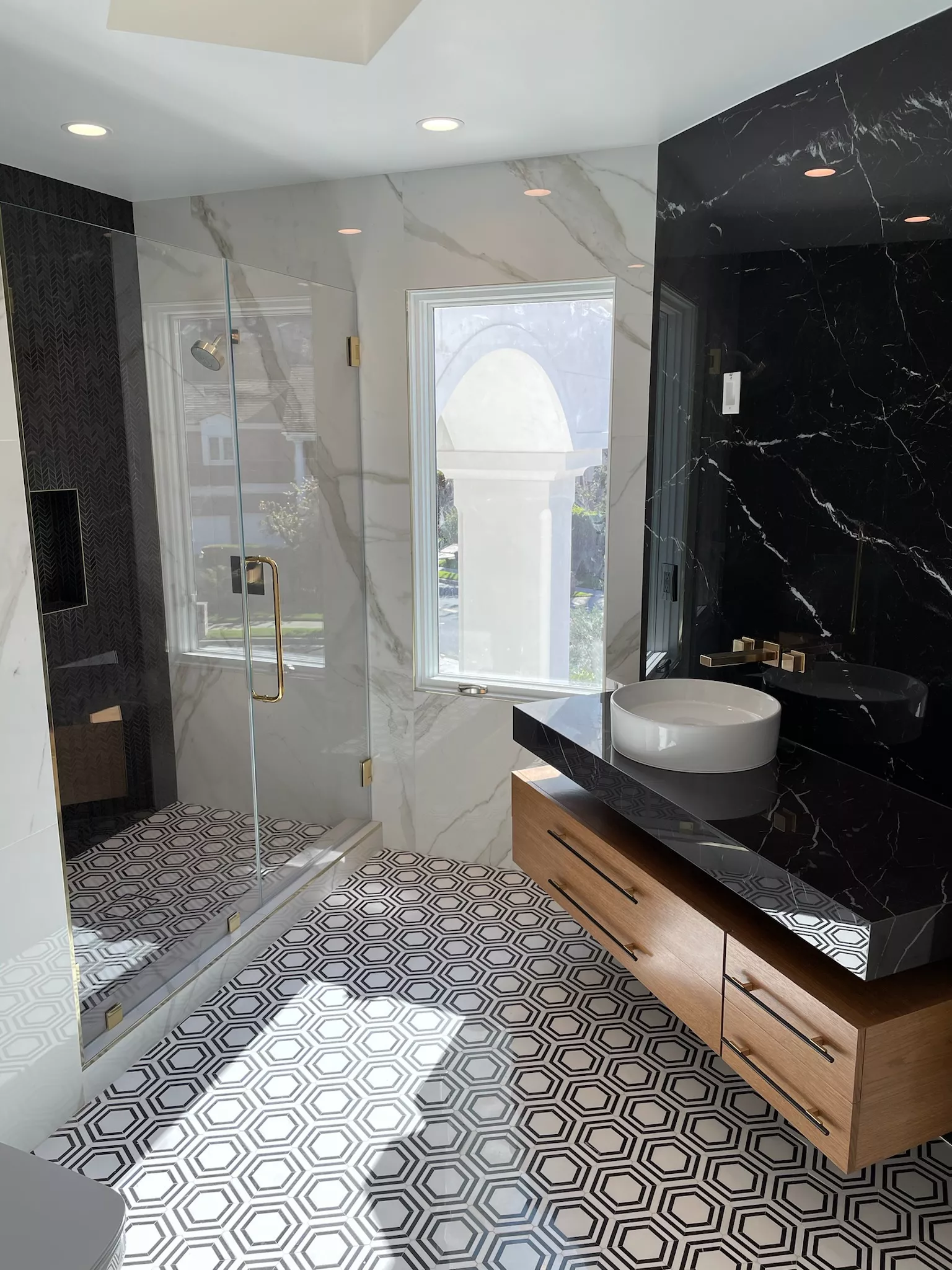 Man with tousled hair sitting at a cluttered desk in a dimly lit room. Warm, orange lighting creates a moody and contemplative atmosphere.