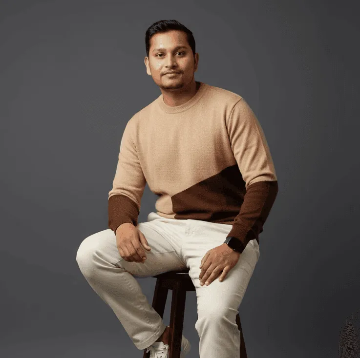 Rahul Gupta (Rahulg), UI/UX Product Designer, seated on stool.