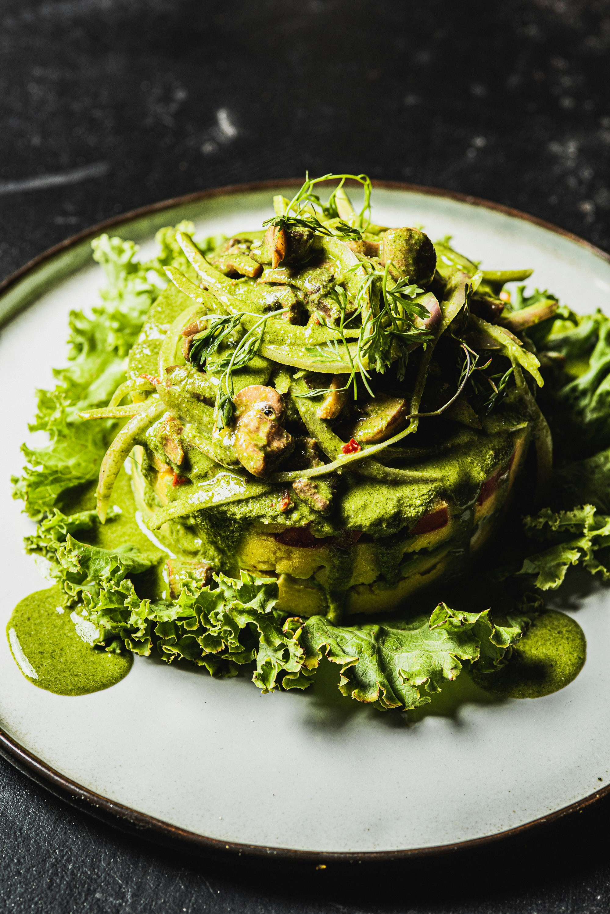 A layered salad with green sauce and lettuce