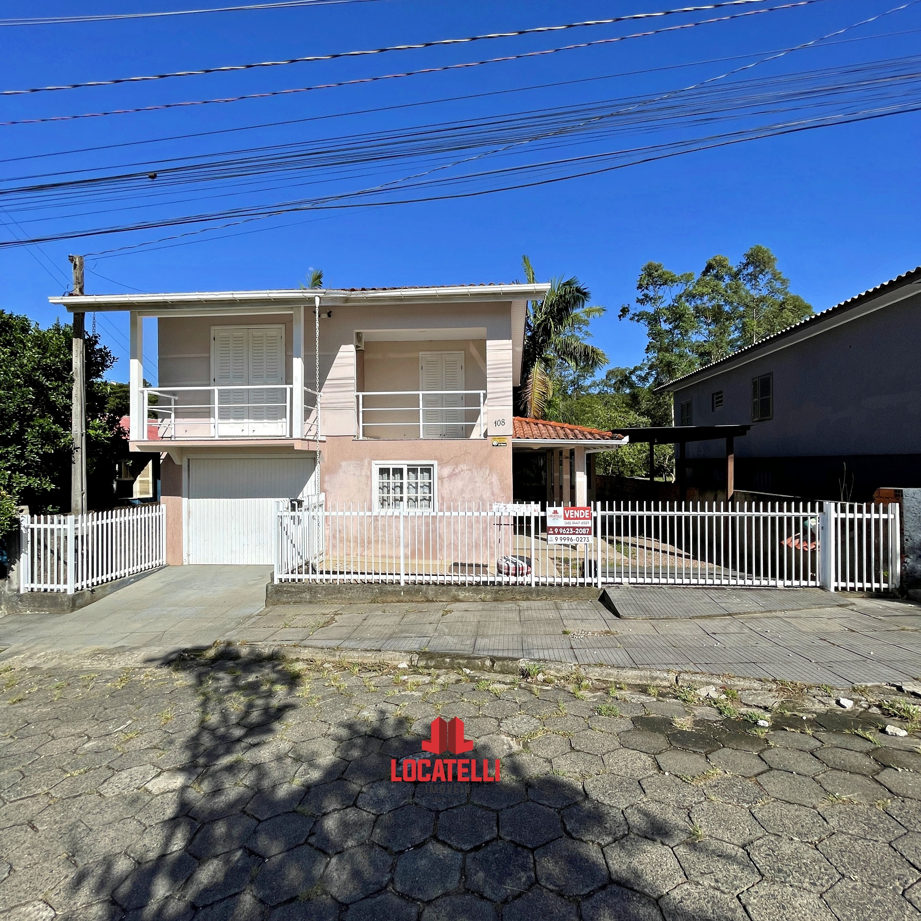 A modern brick house with a two-car garage, well-manicured lawn, and clear blue sky in the background.